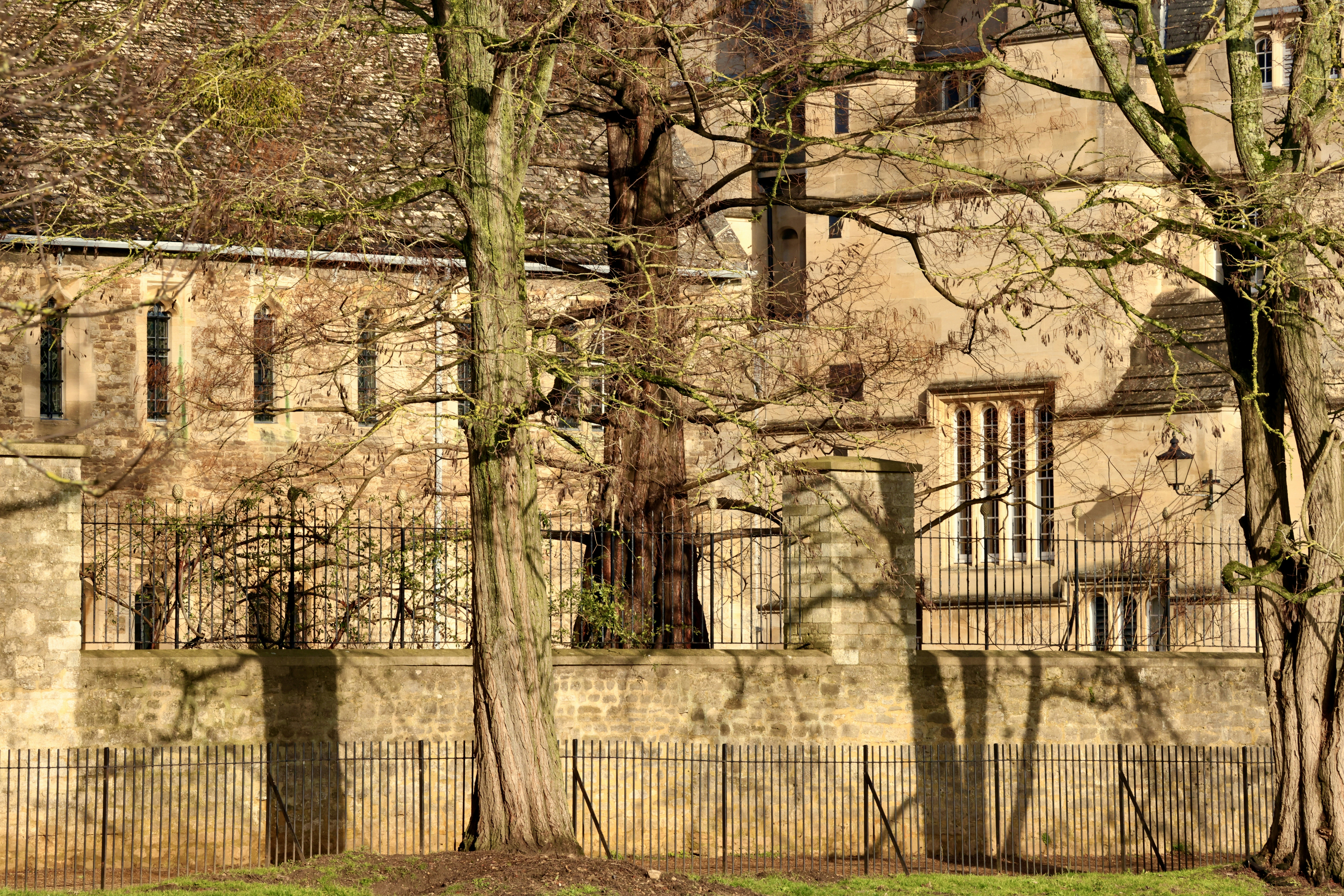 Old stone building with bare trees in foreground.