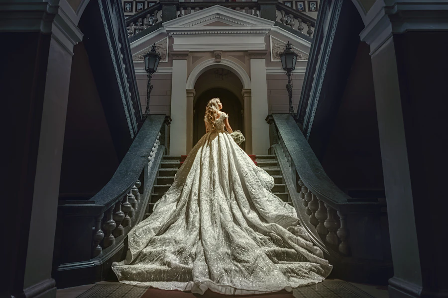 Model in an elaborate gown at the foot of a grand heritage staircase