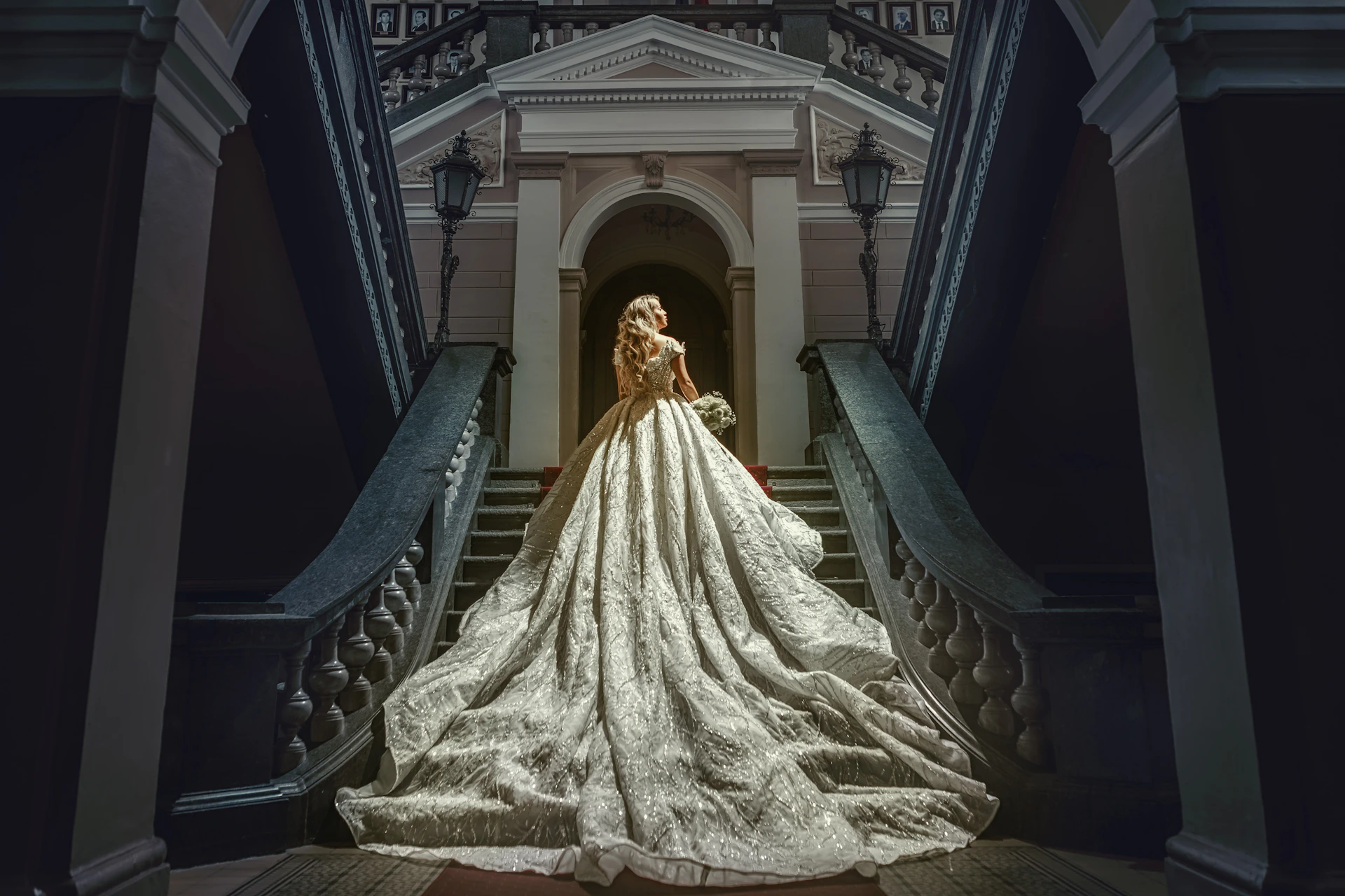 Woman in elaborate white gown on grand staircase