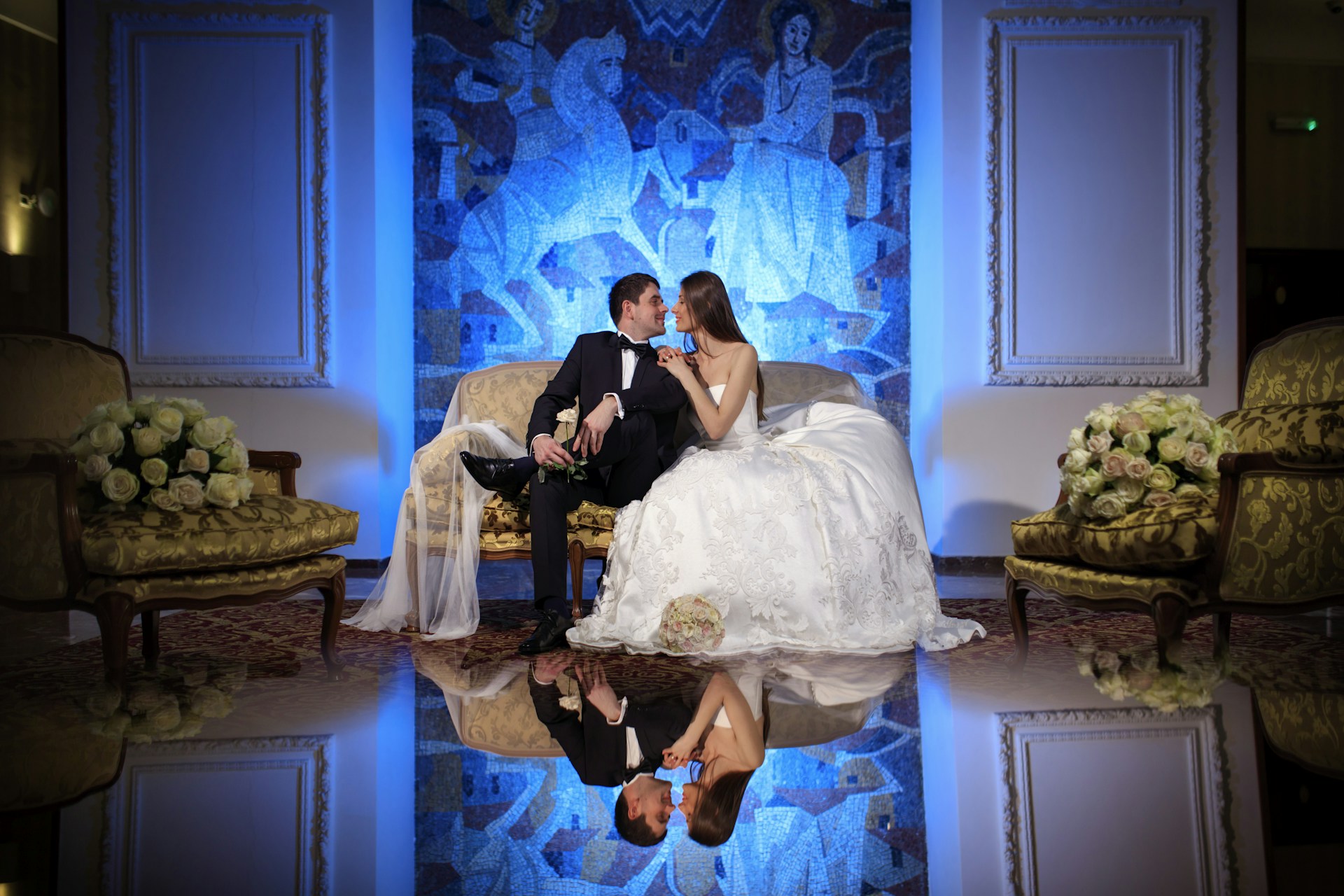 Bride and groom sitting on a couch with reflection