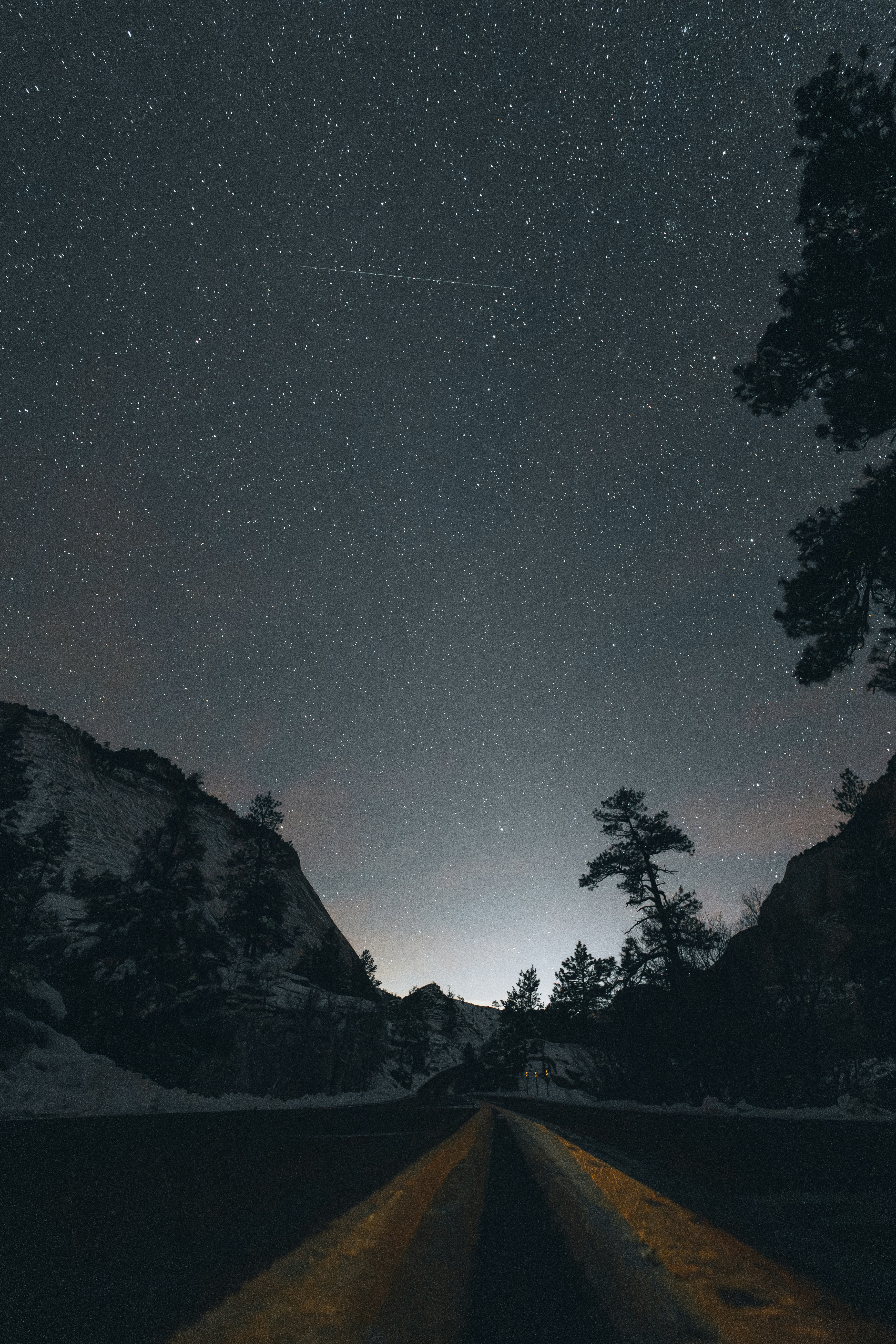A starry night sky over a road between mountains