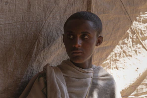 Young person in light-colored robes looks to the side