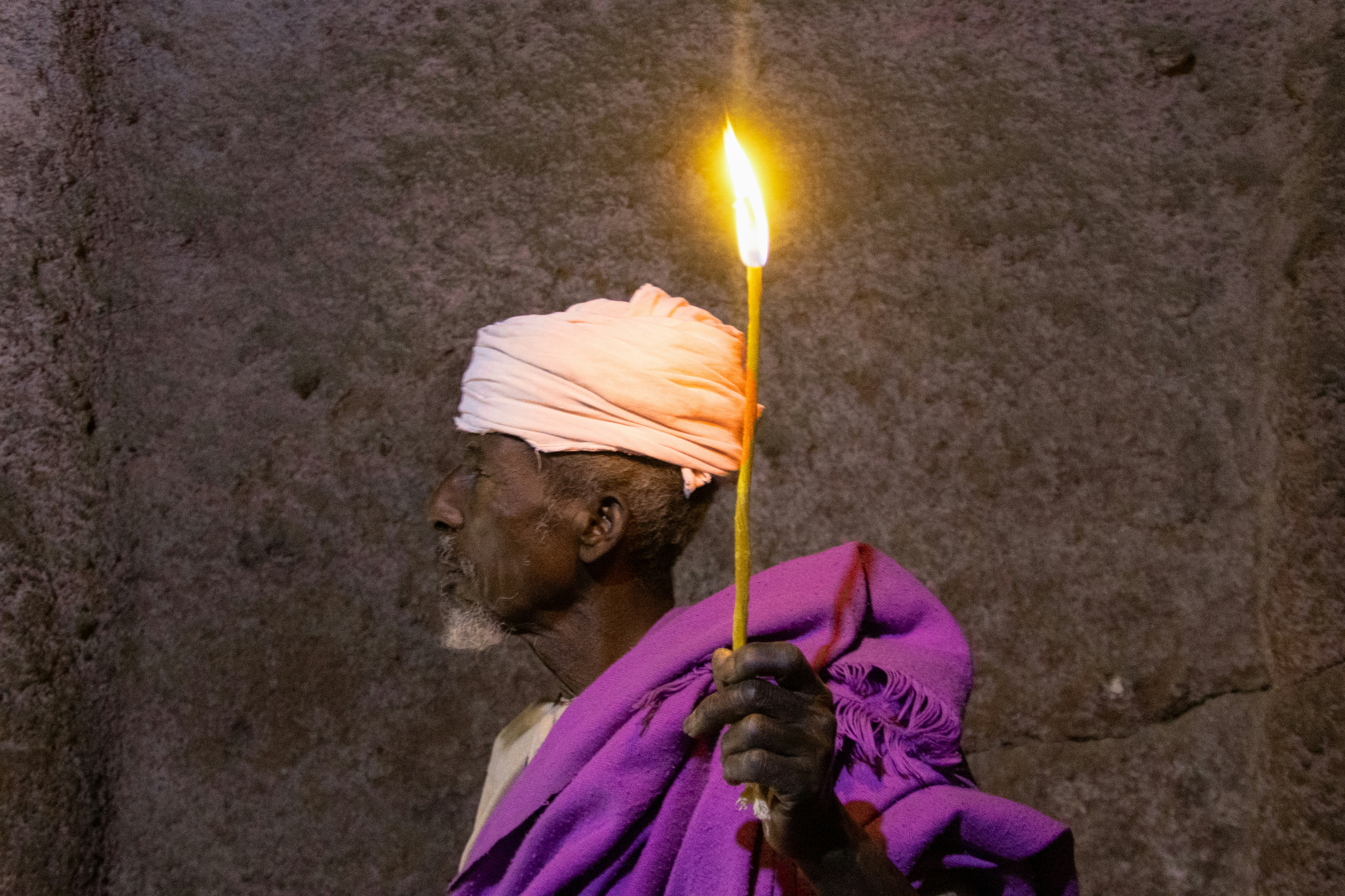 Man in traditional attire holding a lit candle