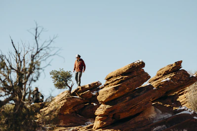 A person hikes on rocky terrain under a clear sky