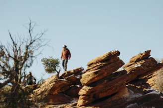 A person hikes on rocky terrain under a clear sky