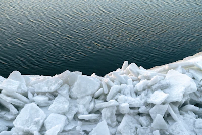 Pile of ice chunks by dark rippling water