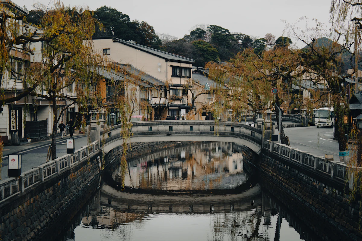Kinosaki Onsen canal lined with traditional ryokan buildings and a stone bridge in autumn, Toyooka, Hyogo, Japan