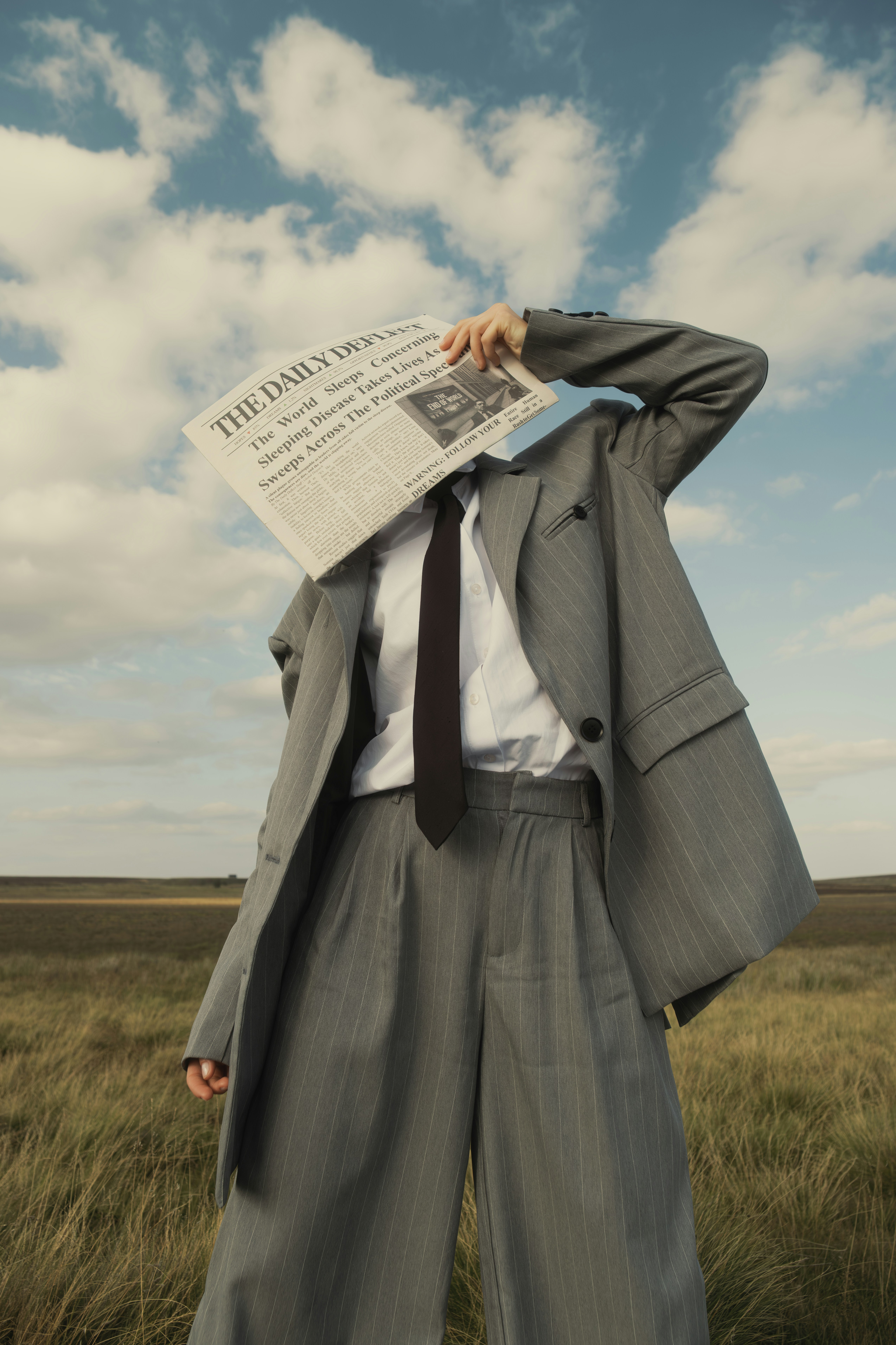 Person in suit holding newspaper over face outdoors