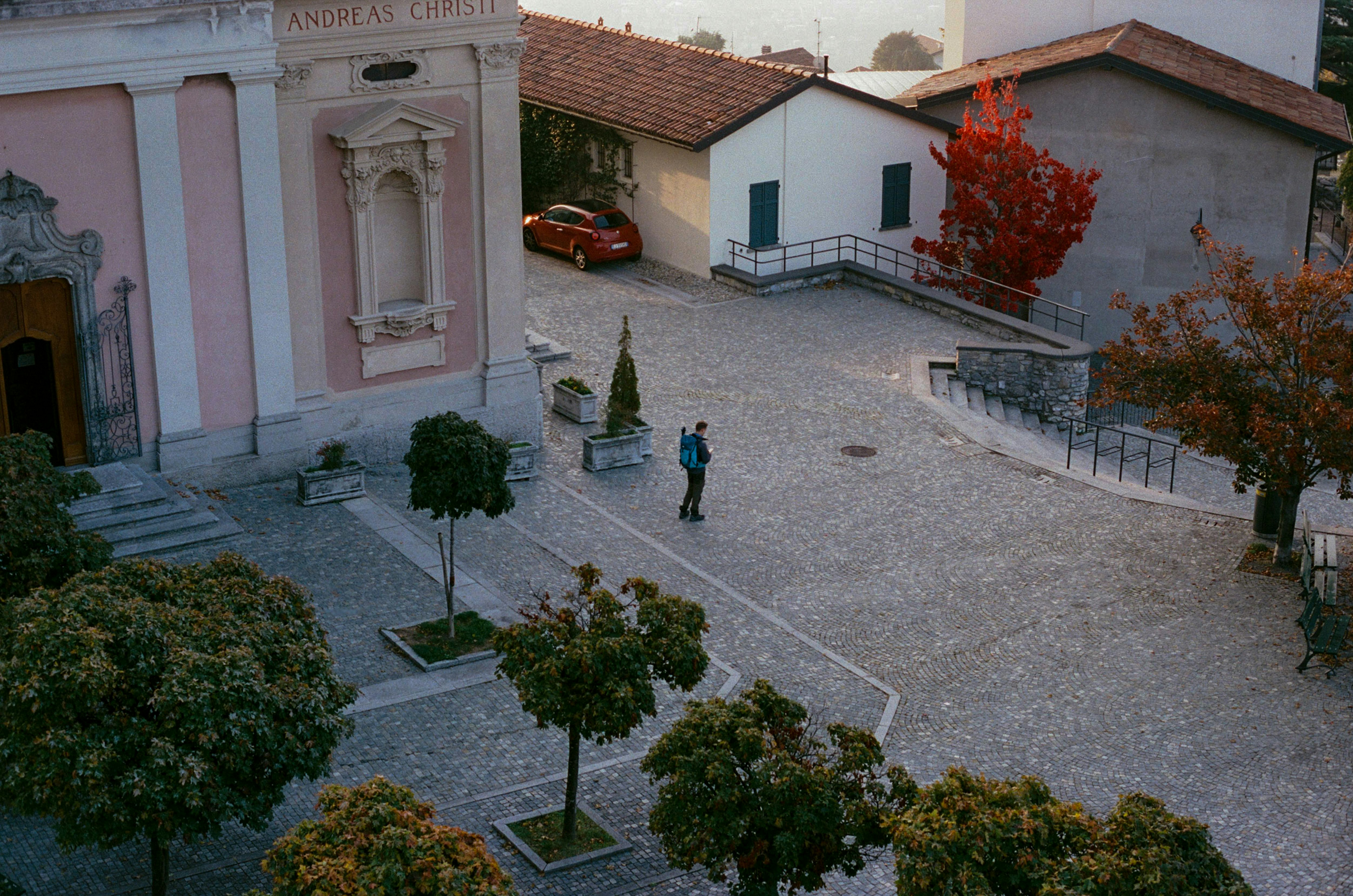 Die Person geht durch einen Kopfsteinpflasterplatz in der Nähe von Gebäuden.