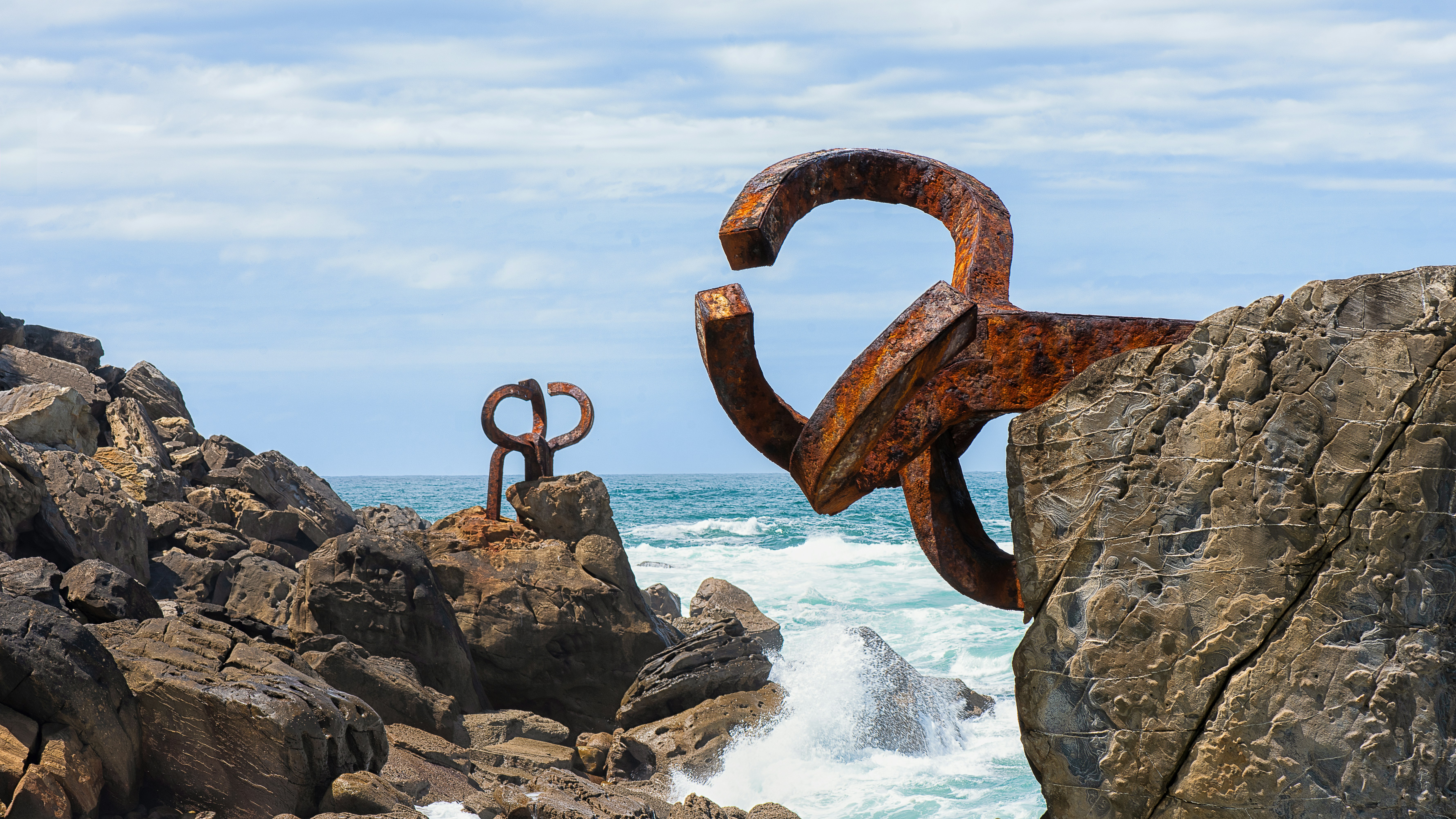 Sculptures on rocky coast with ocean waves crashing