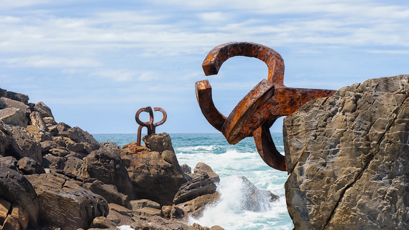 Sculptures on rocky coast with ocean waves crashing