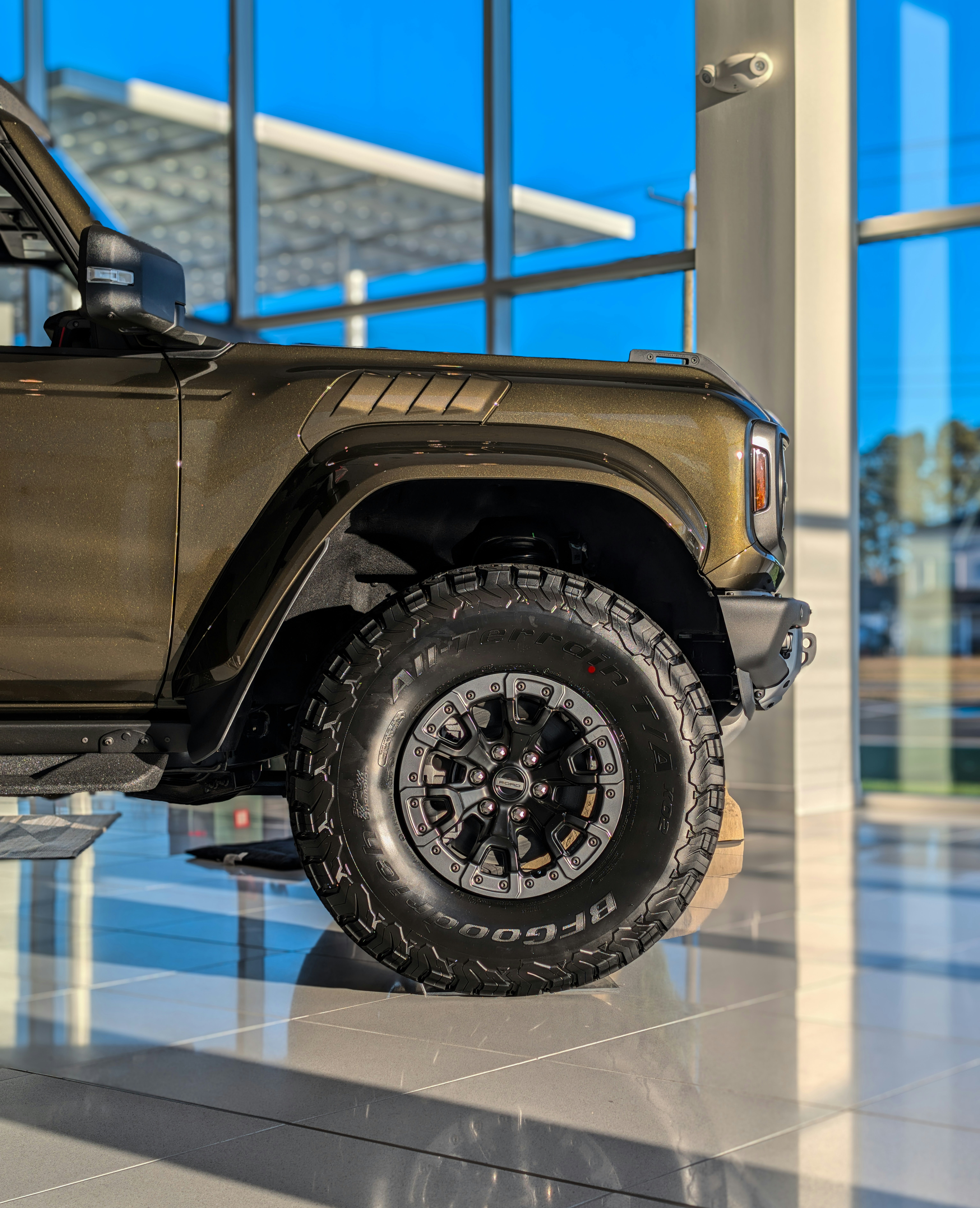 A close-up of a bronze suv's tire and fender.