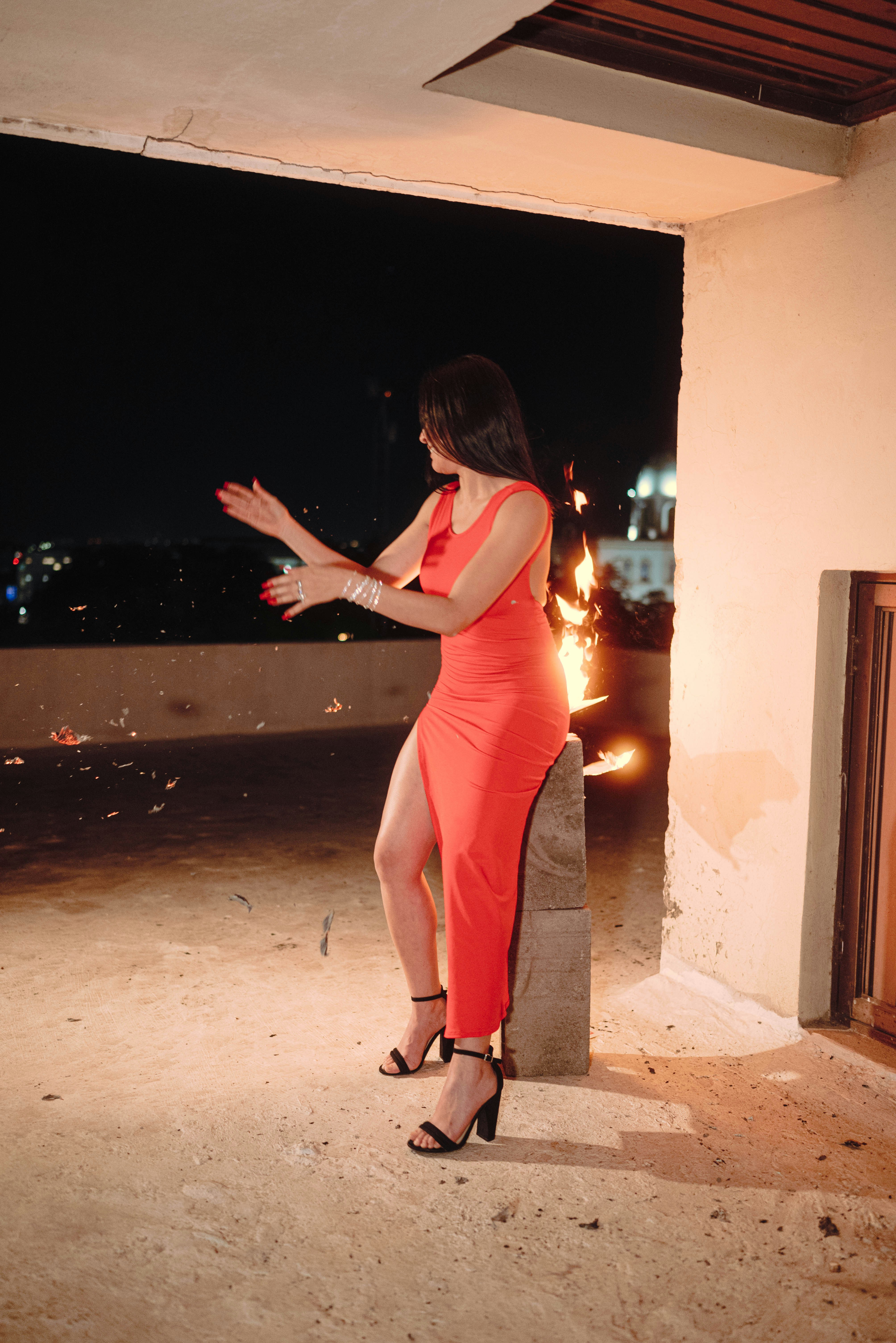 Woman in red dress with fire on a balcony