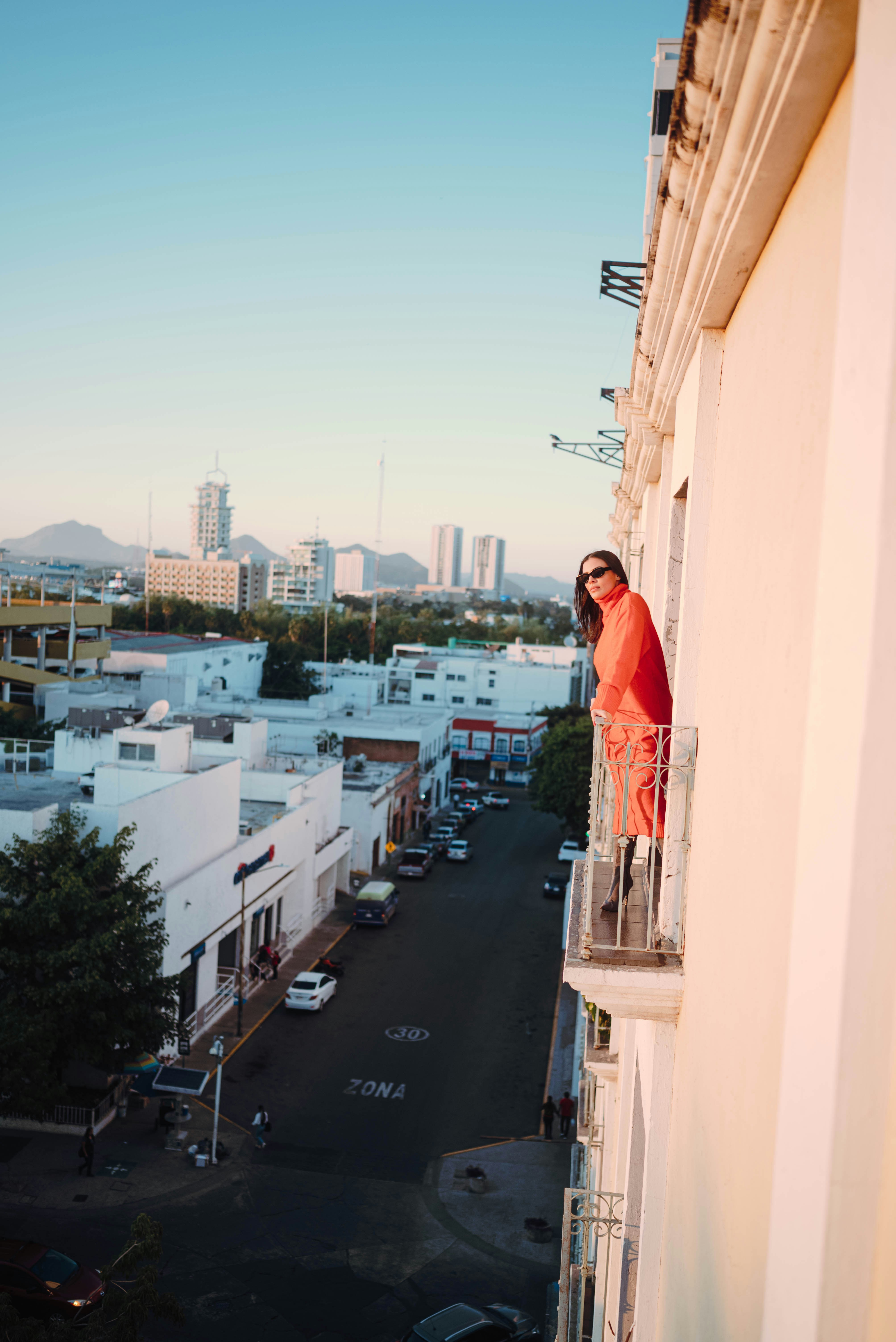Woman in orange on a balcony overlooking city street