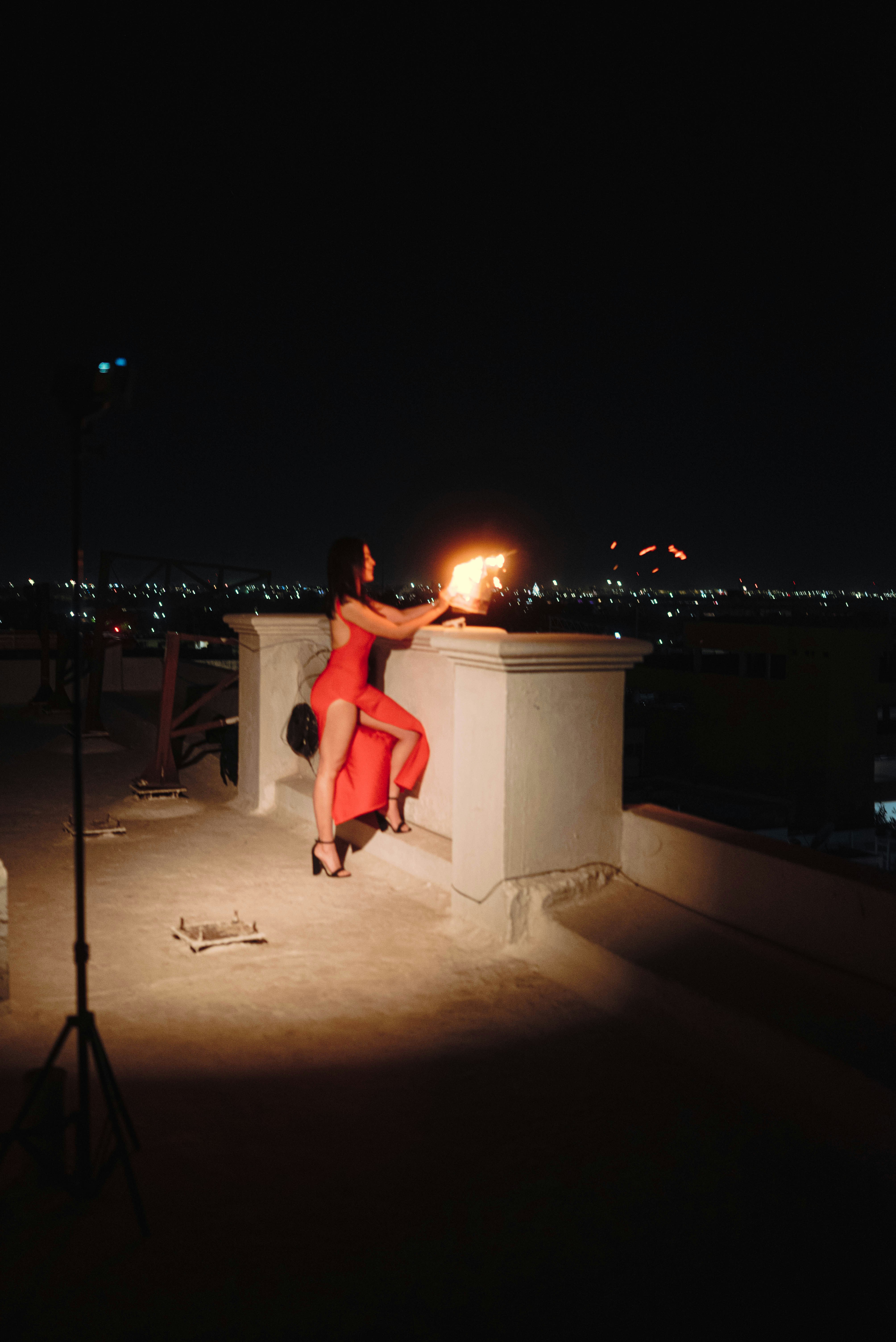 Woman in red dress performs fire dancing at night