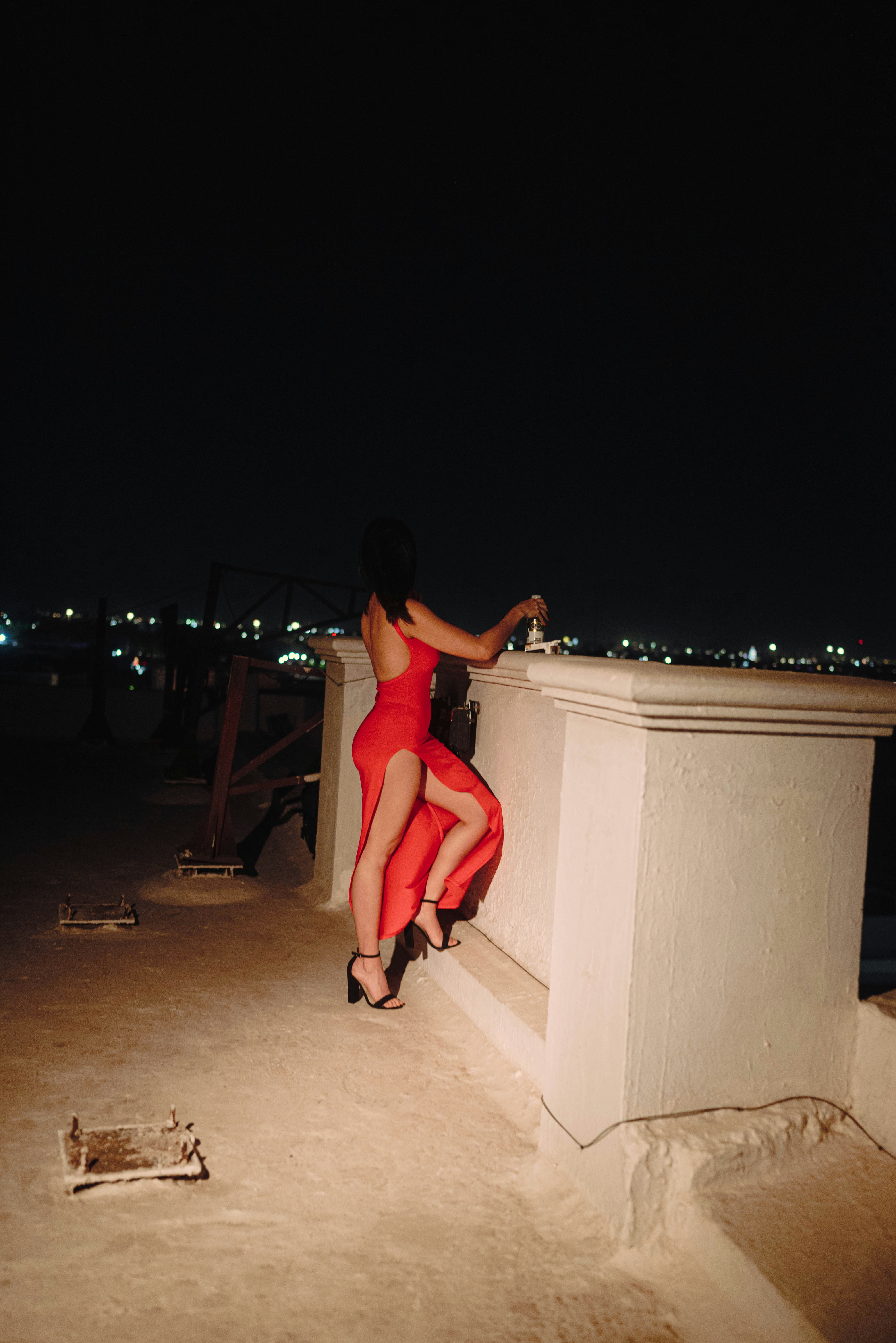 Woman in red dress on rooftop at night