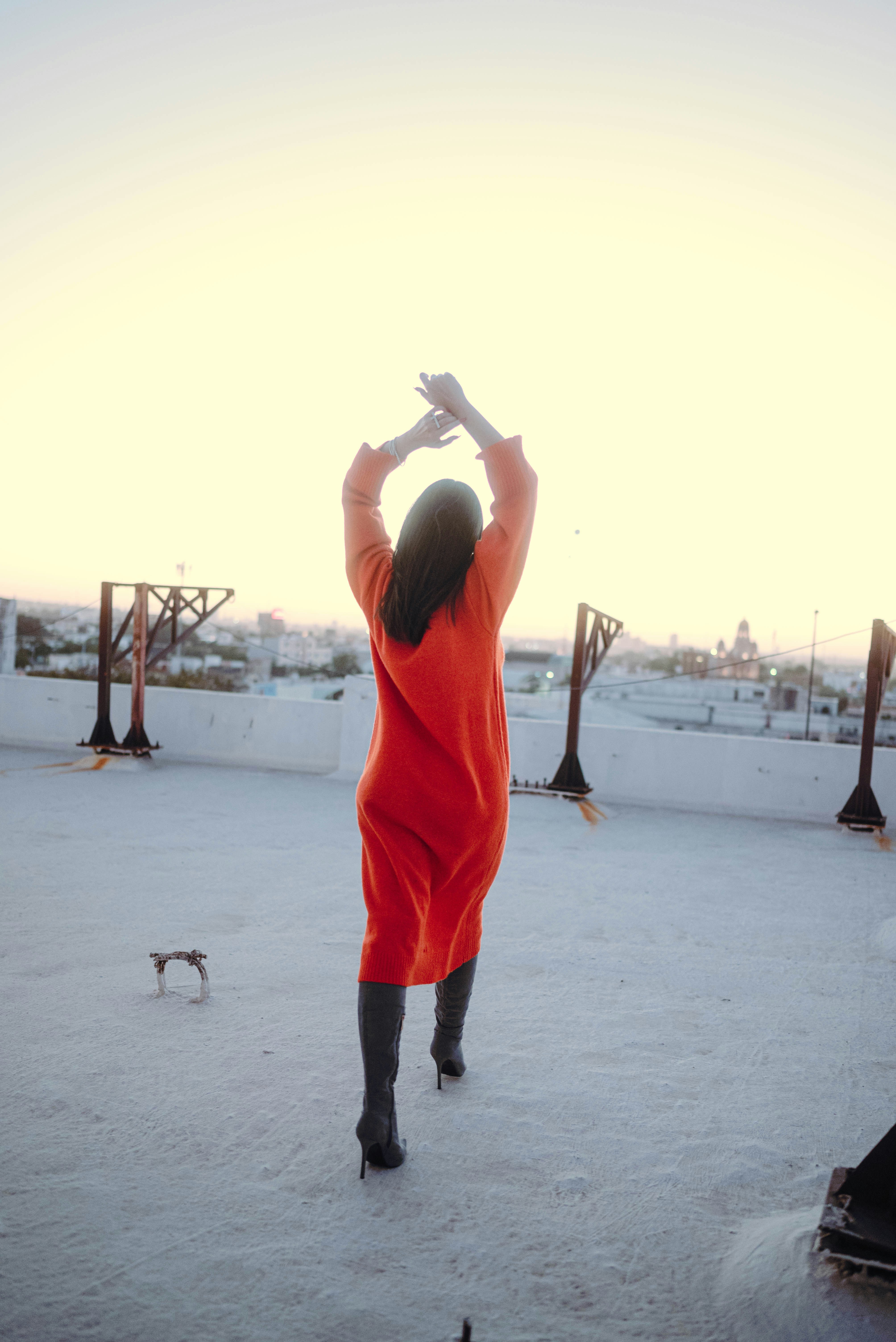 Woman in orange dress on rooftop at sunset
