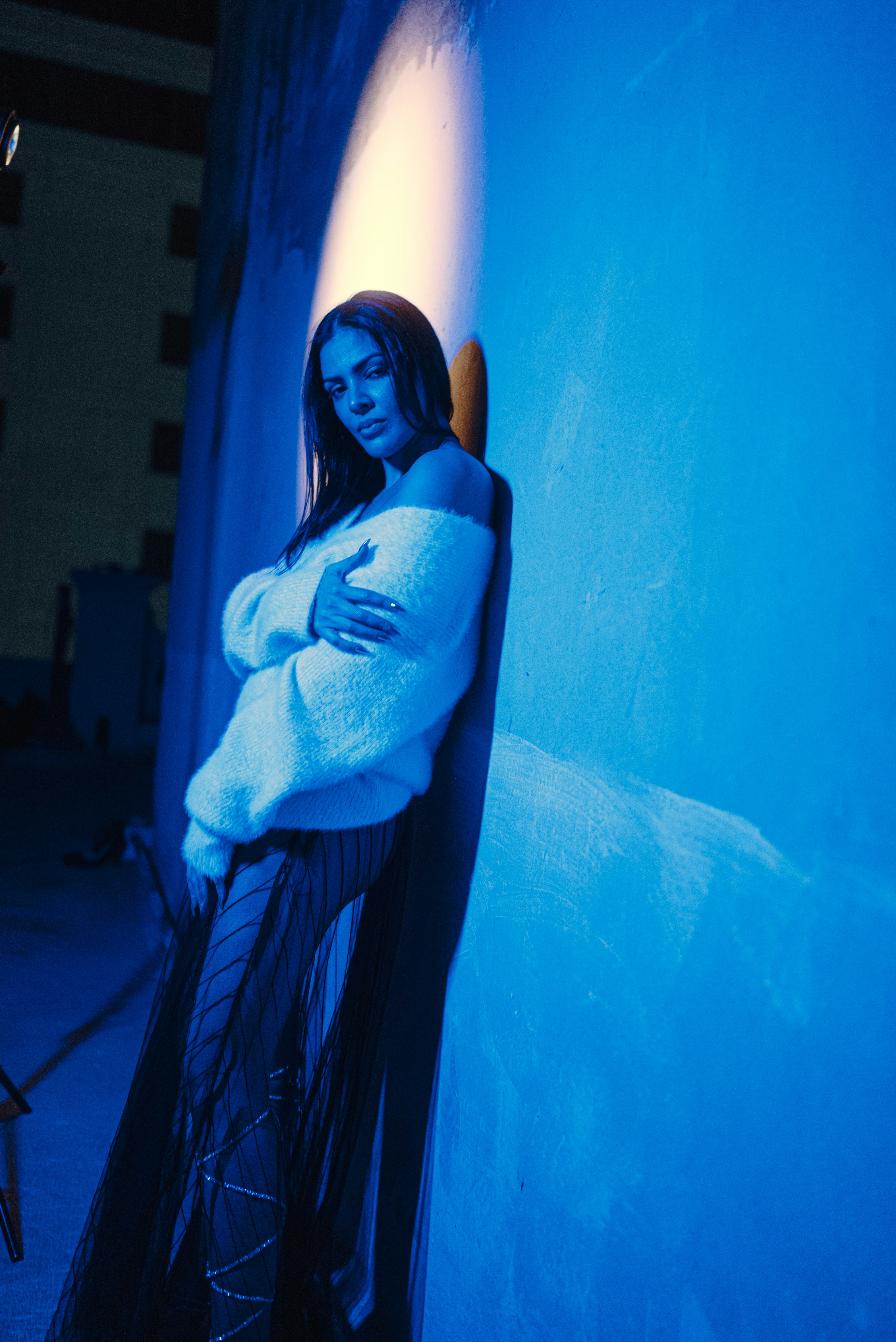Woman leaning against a blue wall with light
