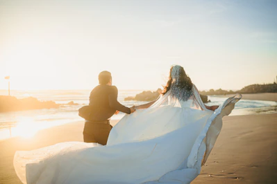 Bride and groom running on a beach at sunset