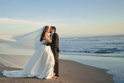Bride and groom kissing on a beach at sunset