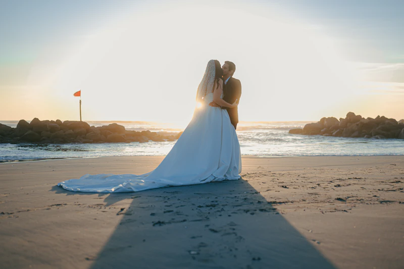 A bride and groom embracing on a sandy beach at golden hour