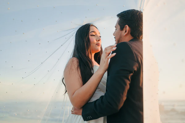 Novios bajo el velo al atardecer