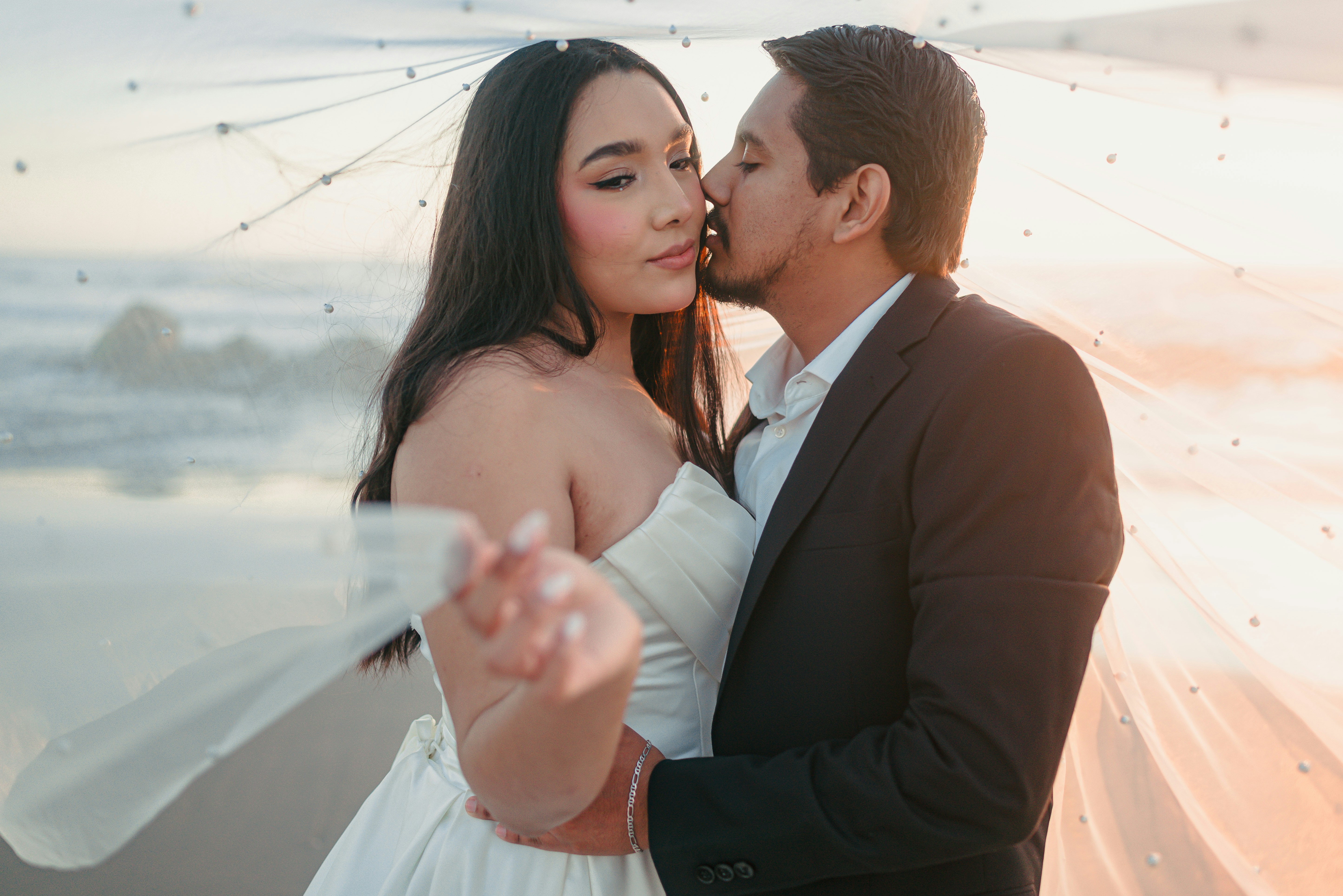 Bride and groom embracing on a beach at sunset