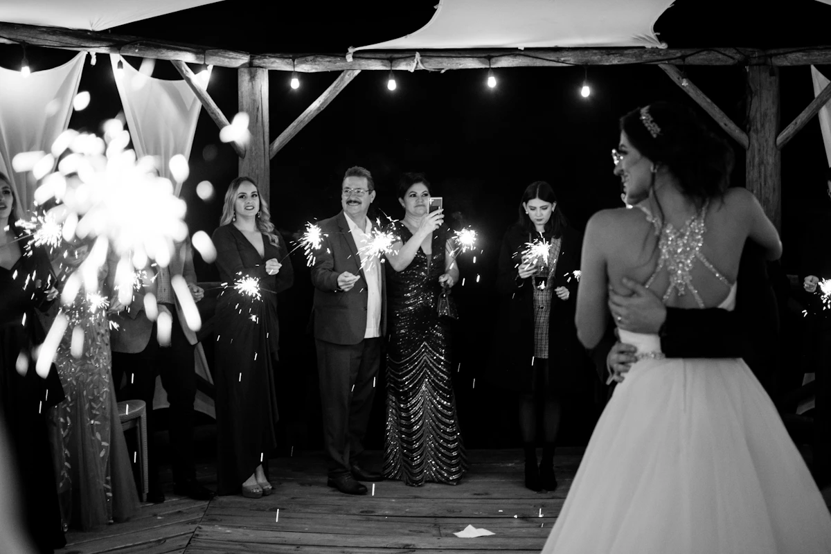 Wedding couple with guests holding sparklers at night