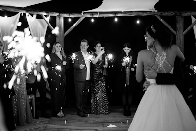 Wedding couple with guests holding sparklers at night