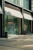 Modern building entrance with awnings and plants.