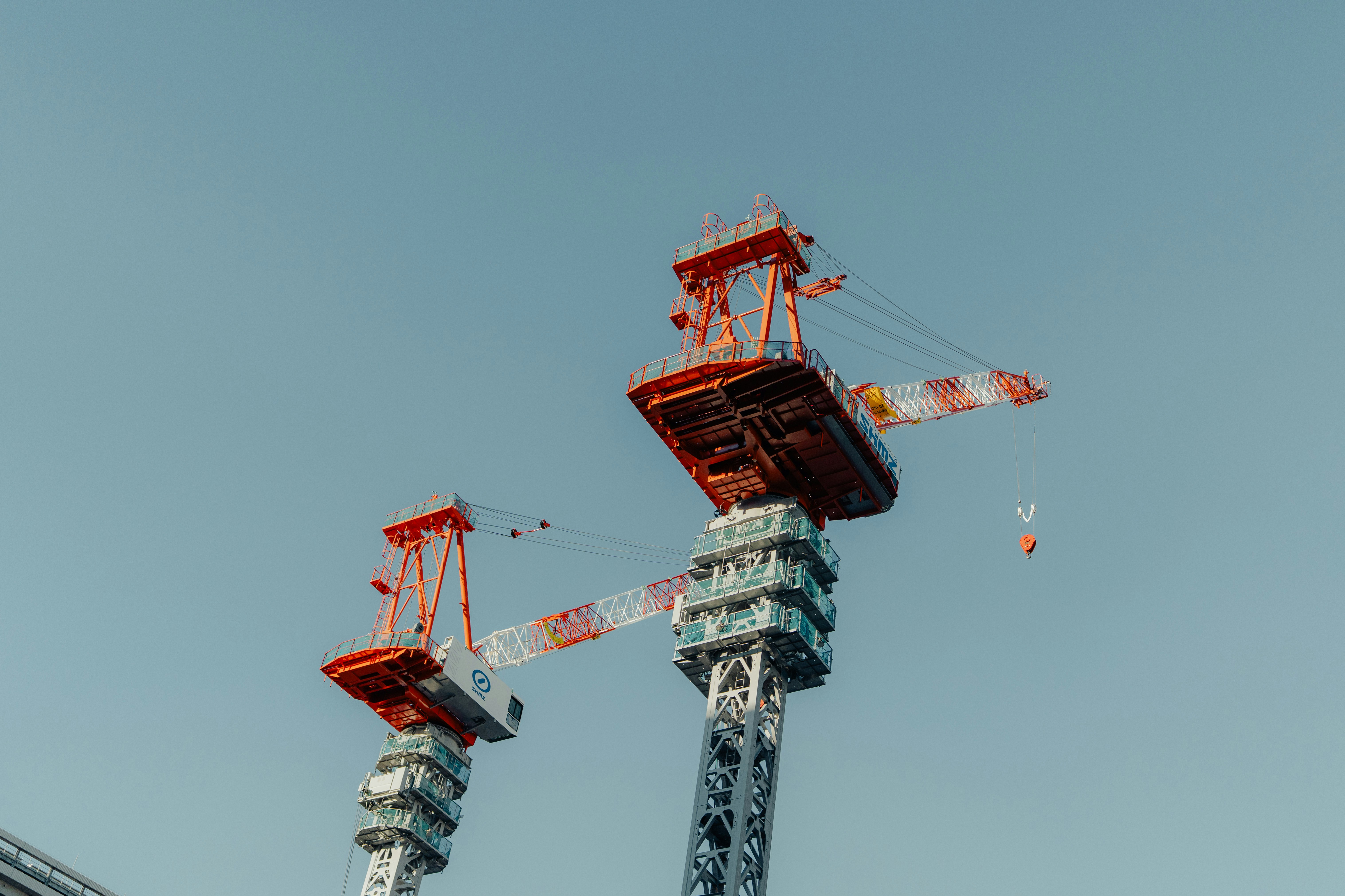 Two large construction cranes against a clear sky
