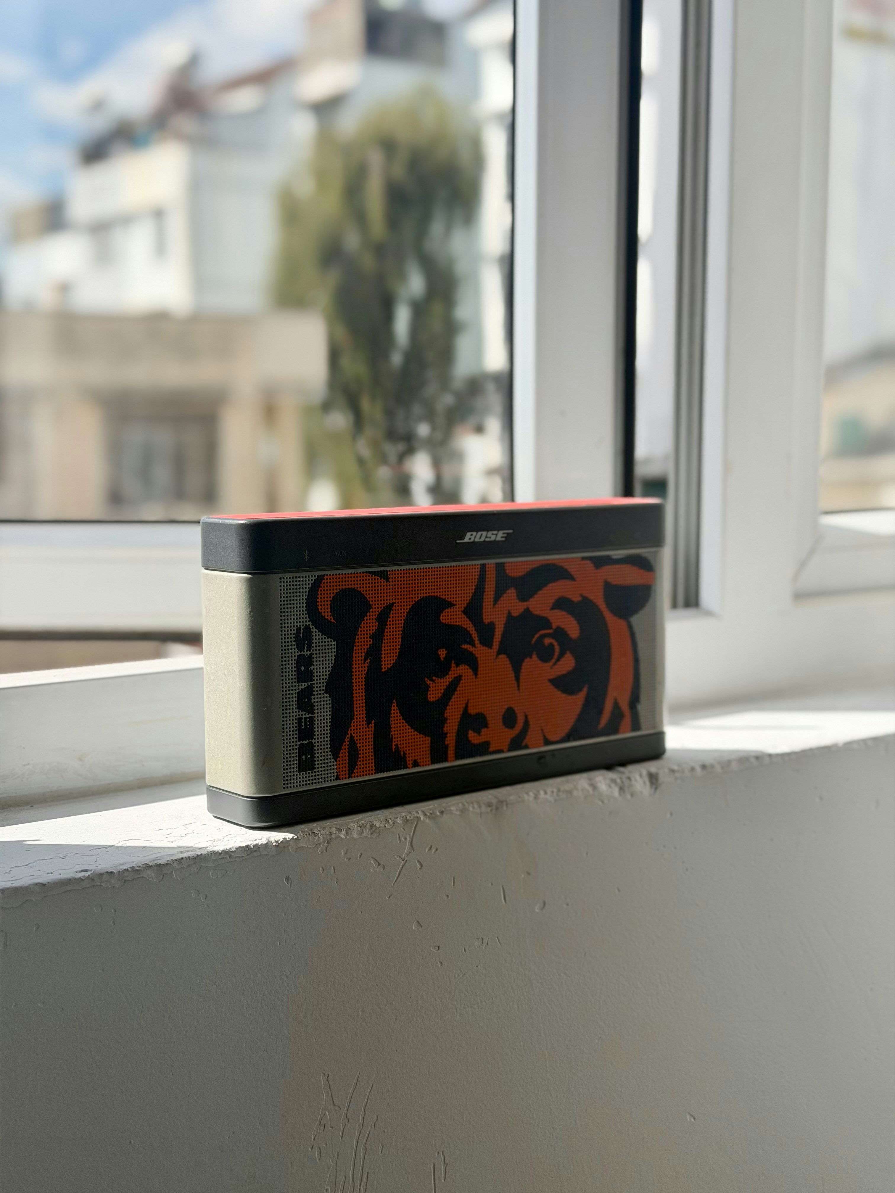 Speaker Bose dengan logo beruang chicago di ambang jendela