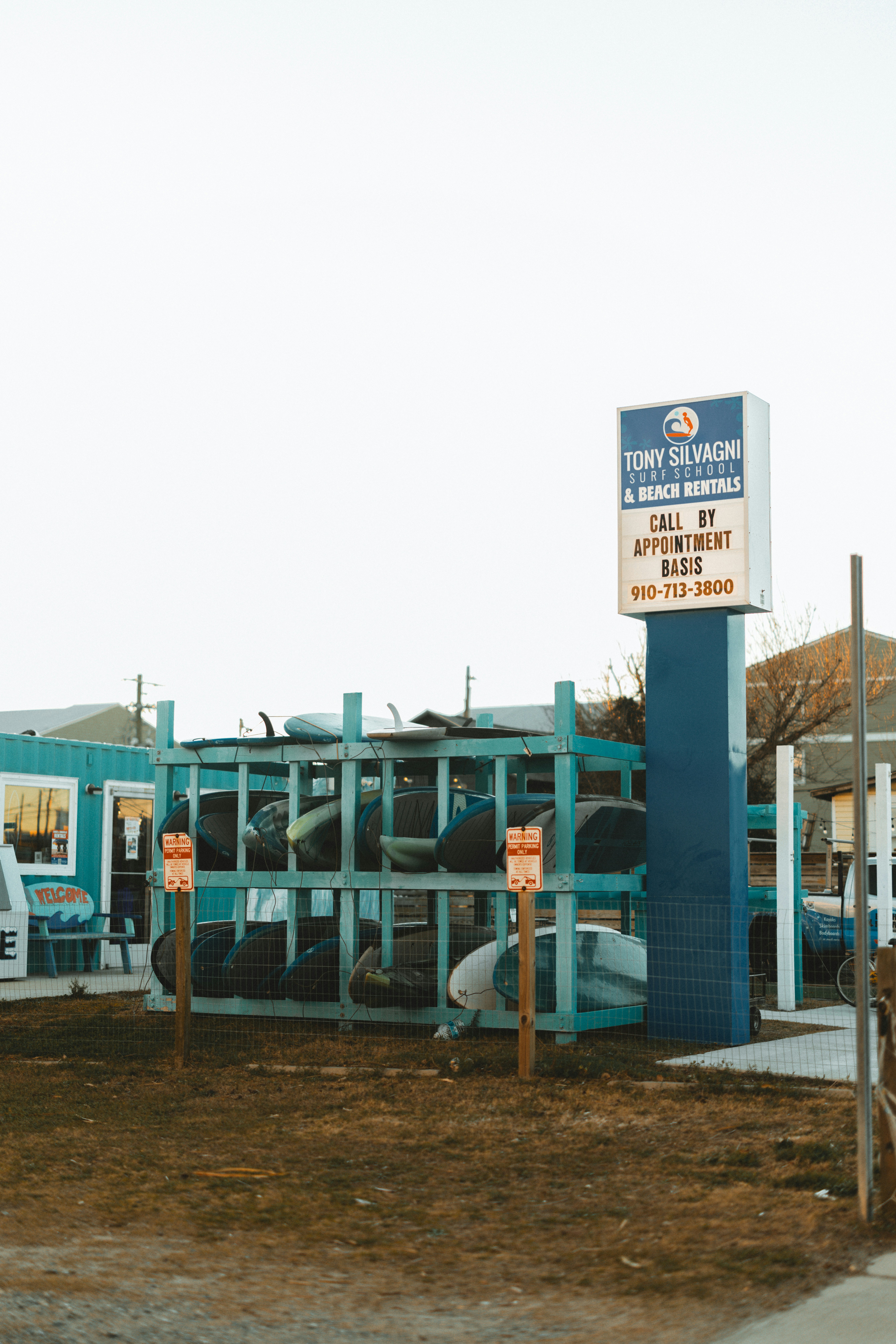 Surfboards stacked on racks outside a rental shop.