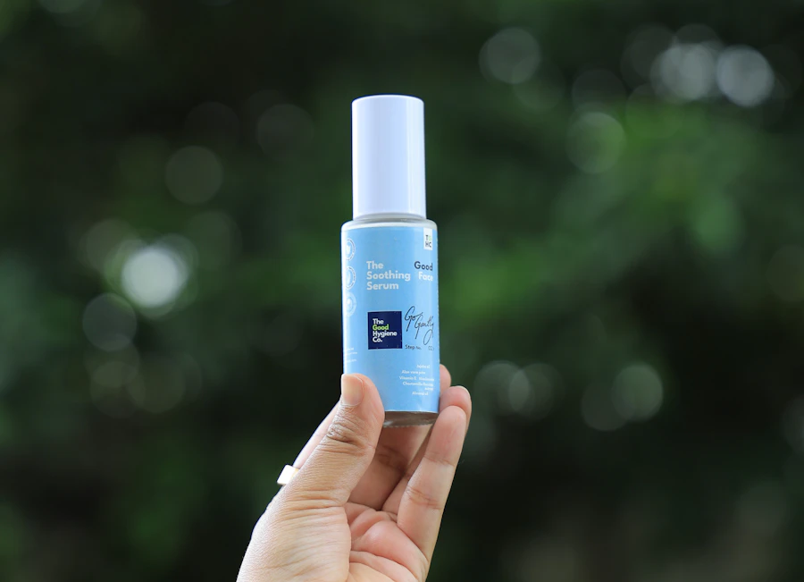 Hand holding a bottle of blue serum outdoors
