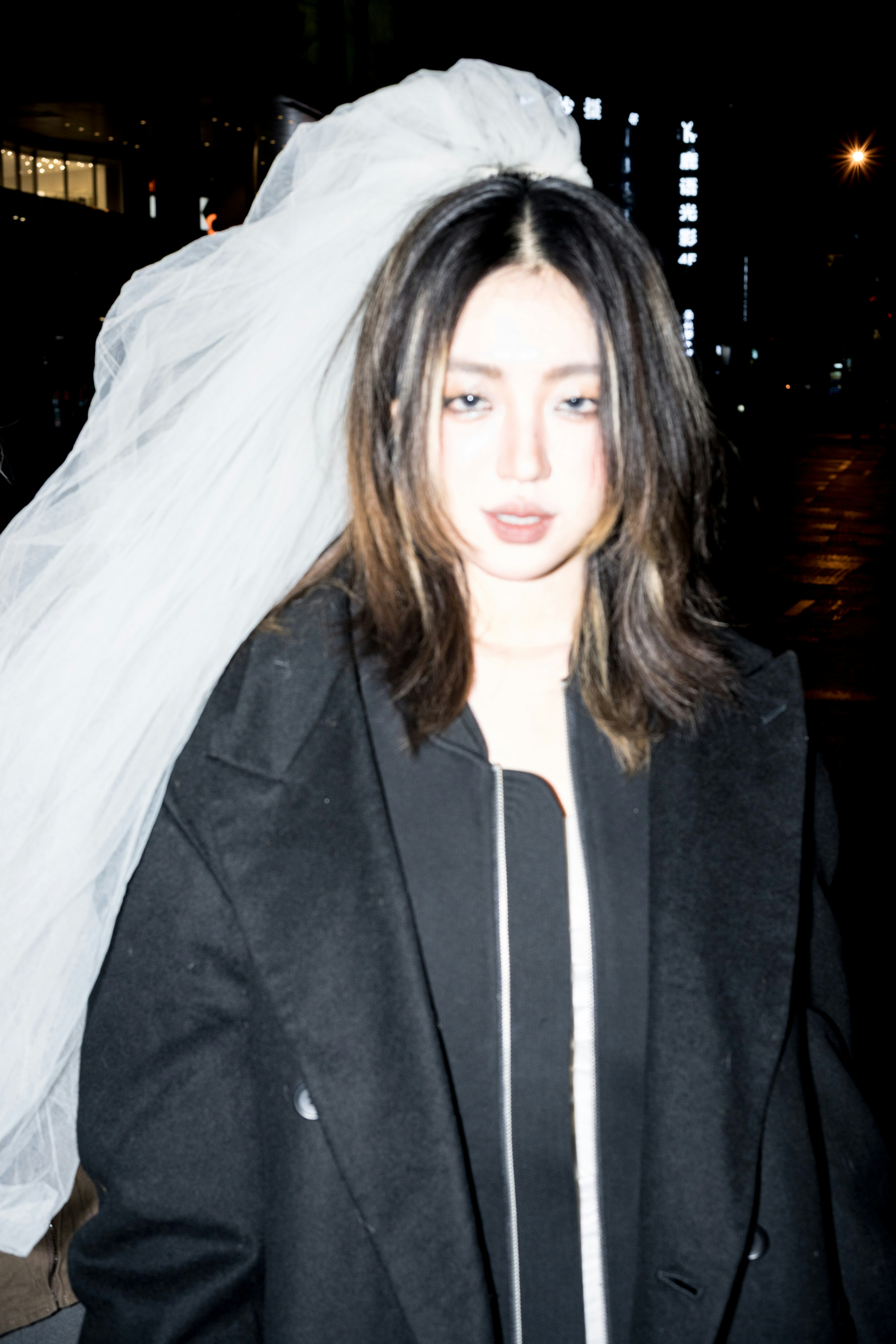 Woman in dark coat with veil at night