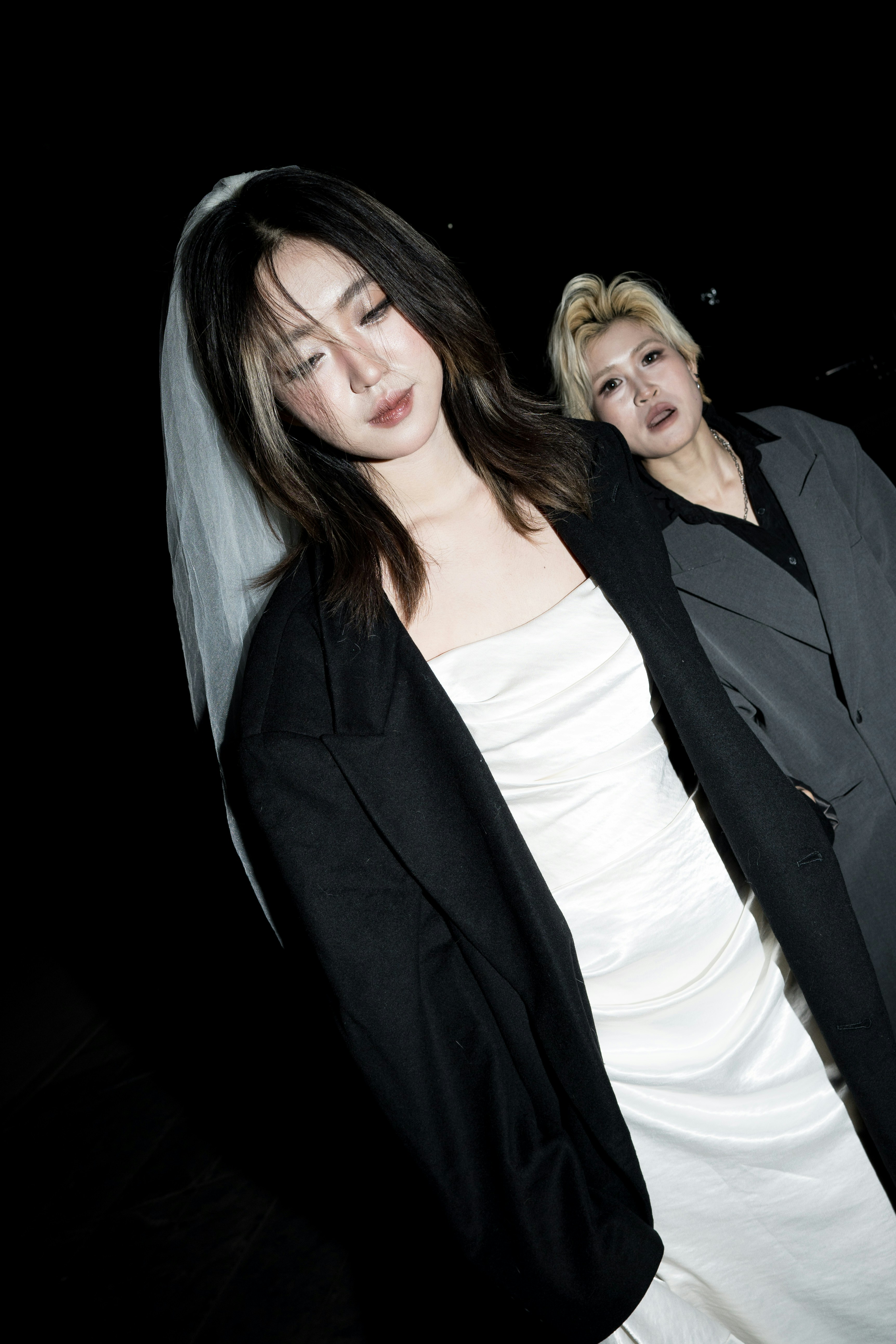 Two women in formal wear with a veil