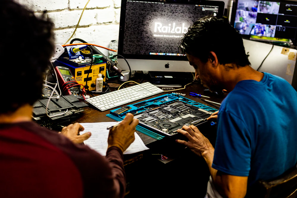 Two technicians examining a phone motherboard at the bench