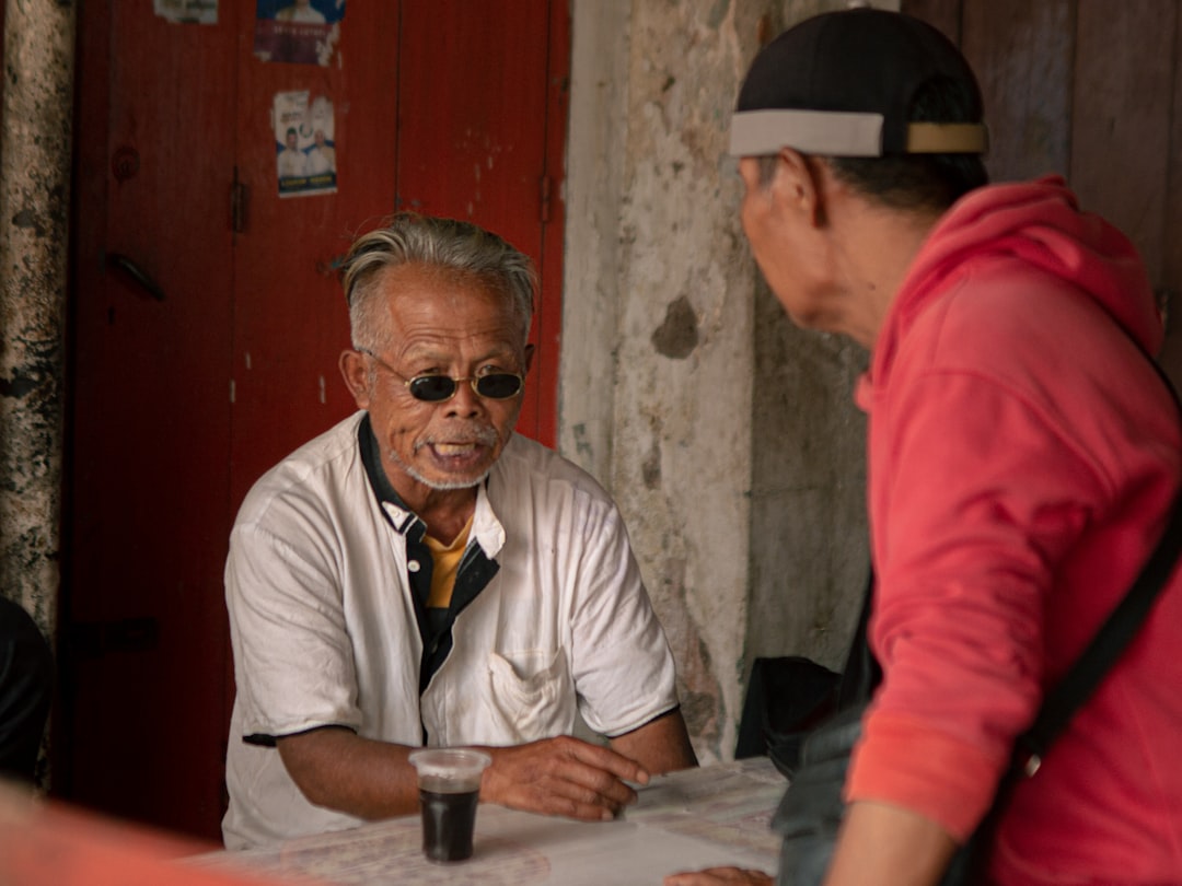 Two men talking at a table with a drink.