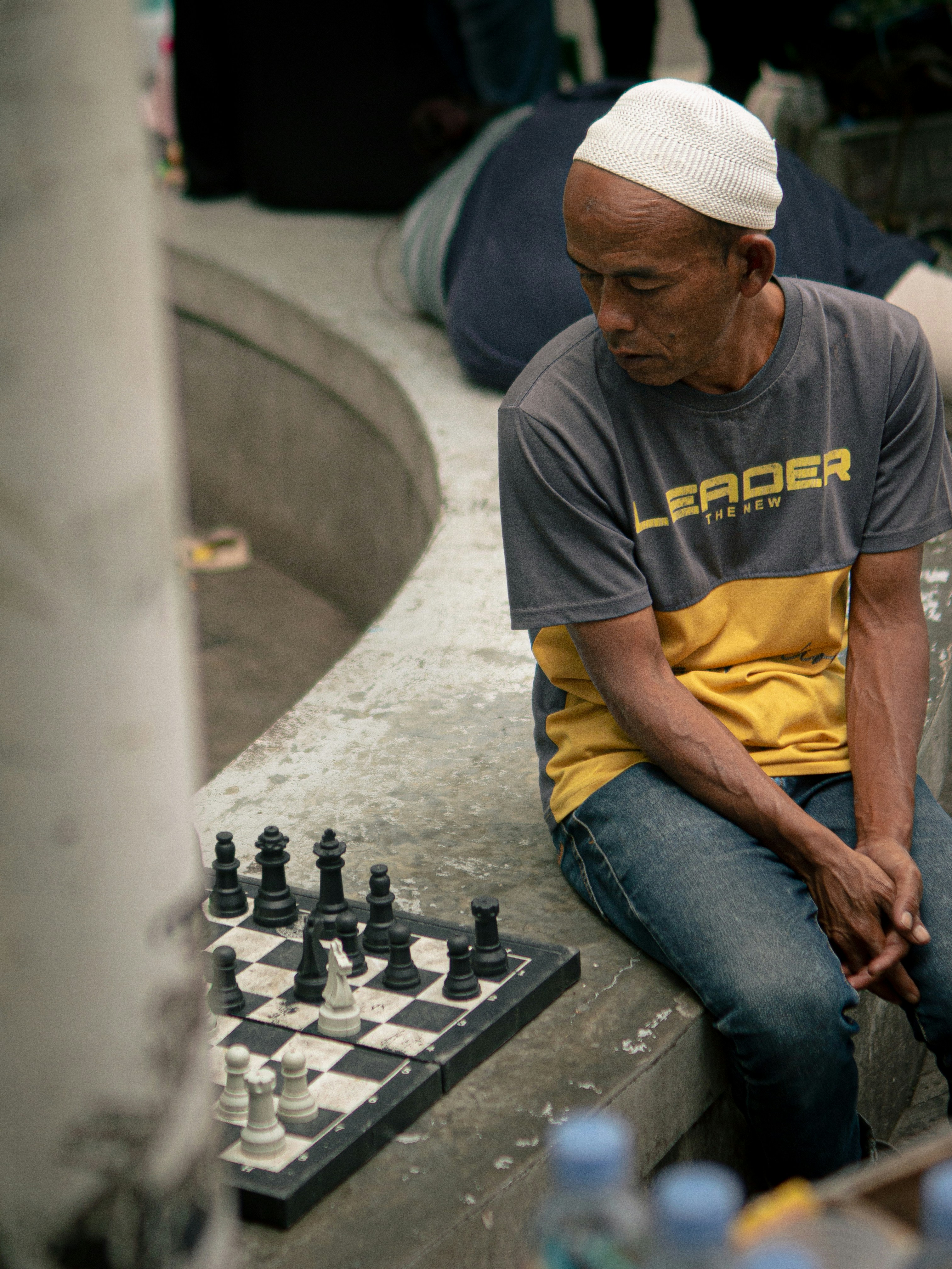 コンクリートのベンチでチェスをしている男。