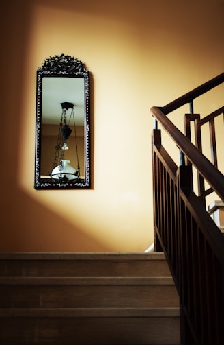 A wooden staircase with a mirror on the wall.