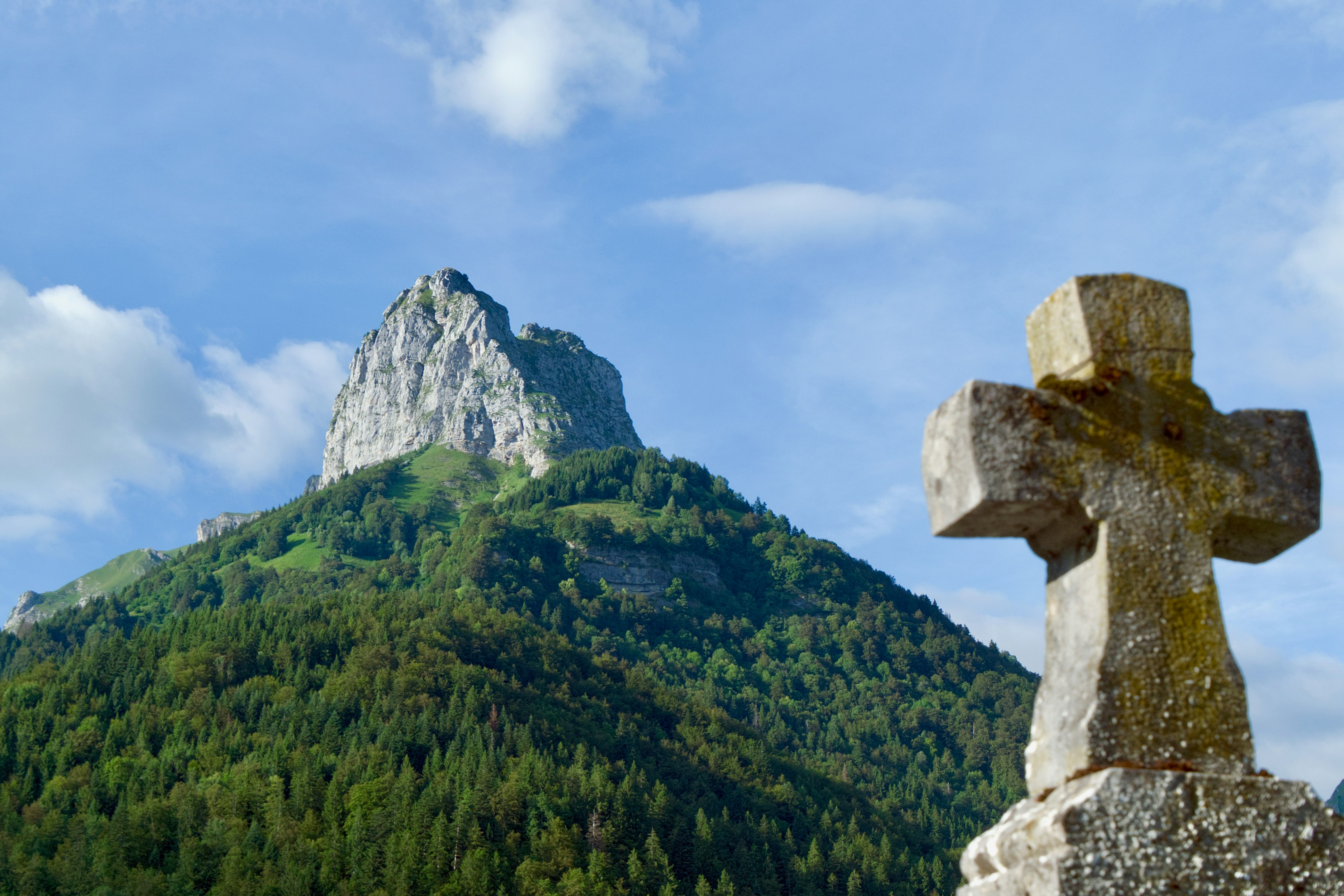 Stone cross in front of a mountain peak.