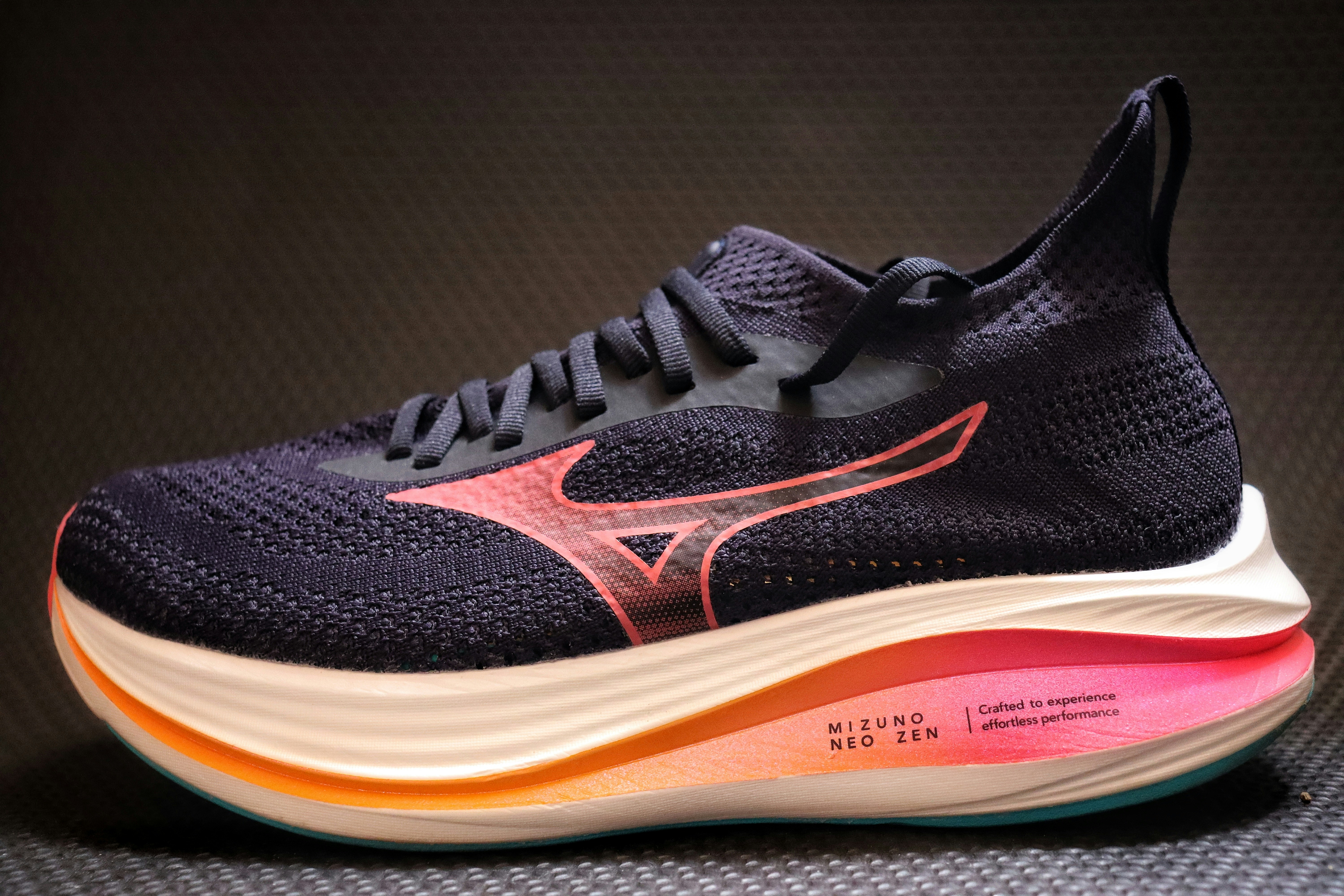 A dark blue athletic shoe with pink accents.