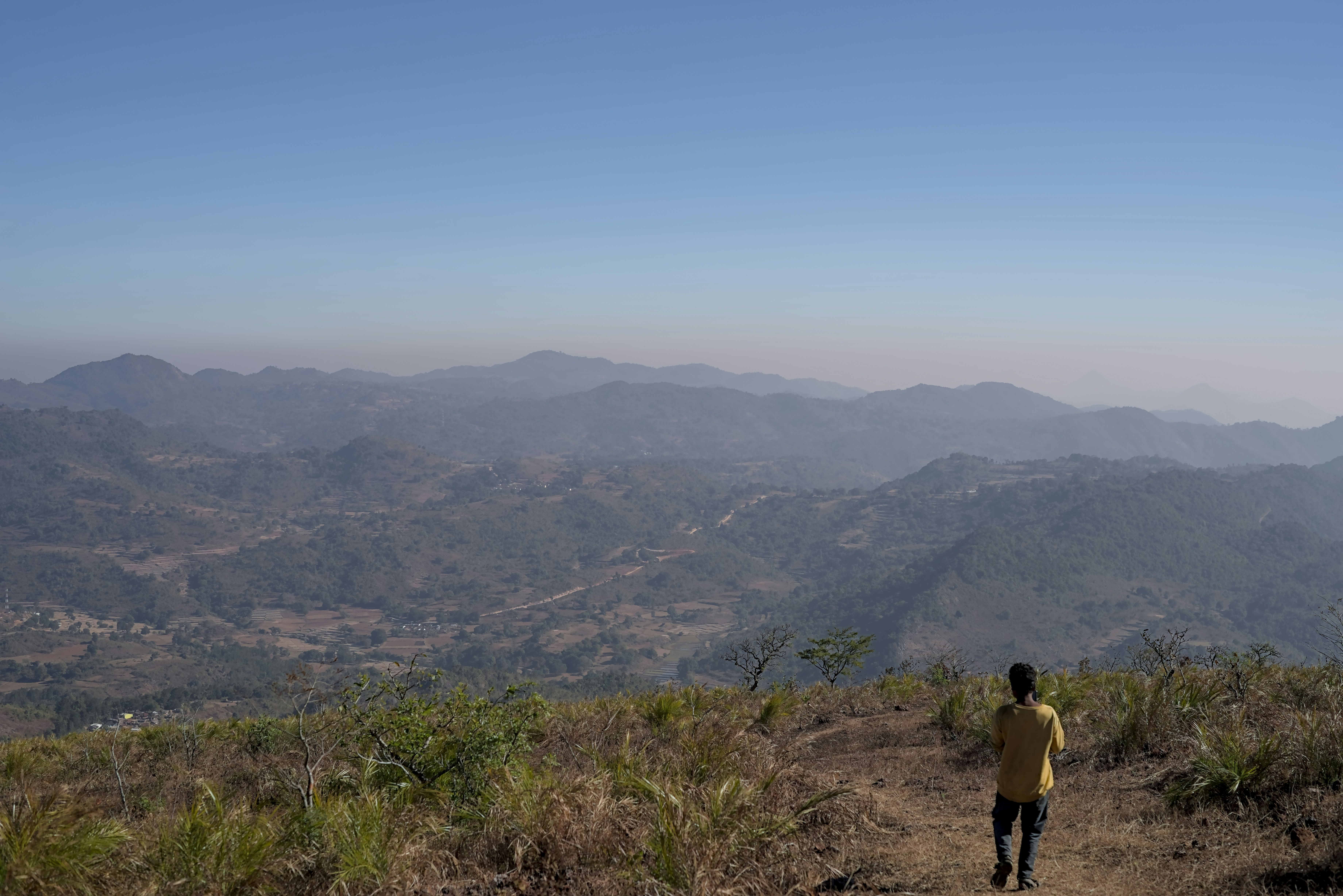 Man standing on a mountain overlooking hills