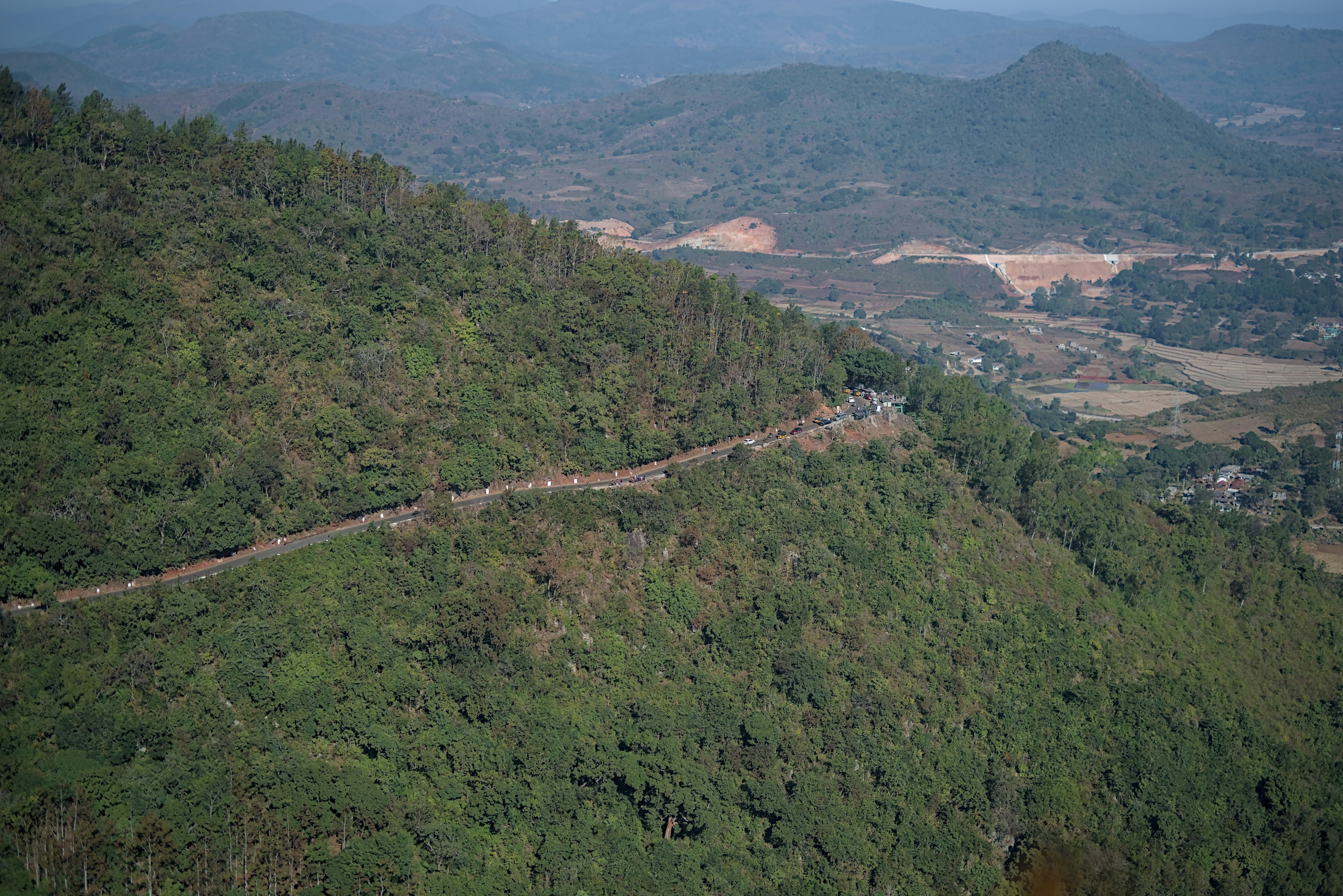 A winding road cuts through a lush green mountainside.