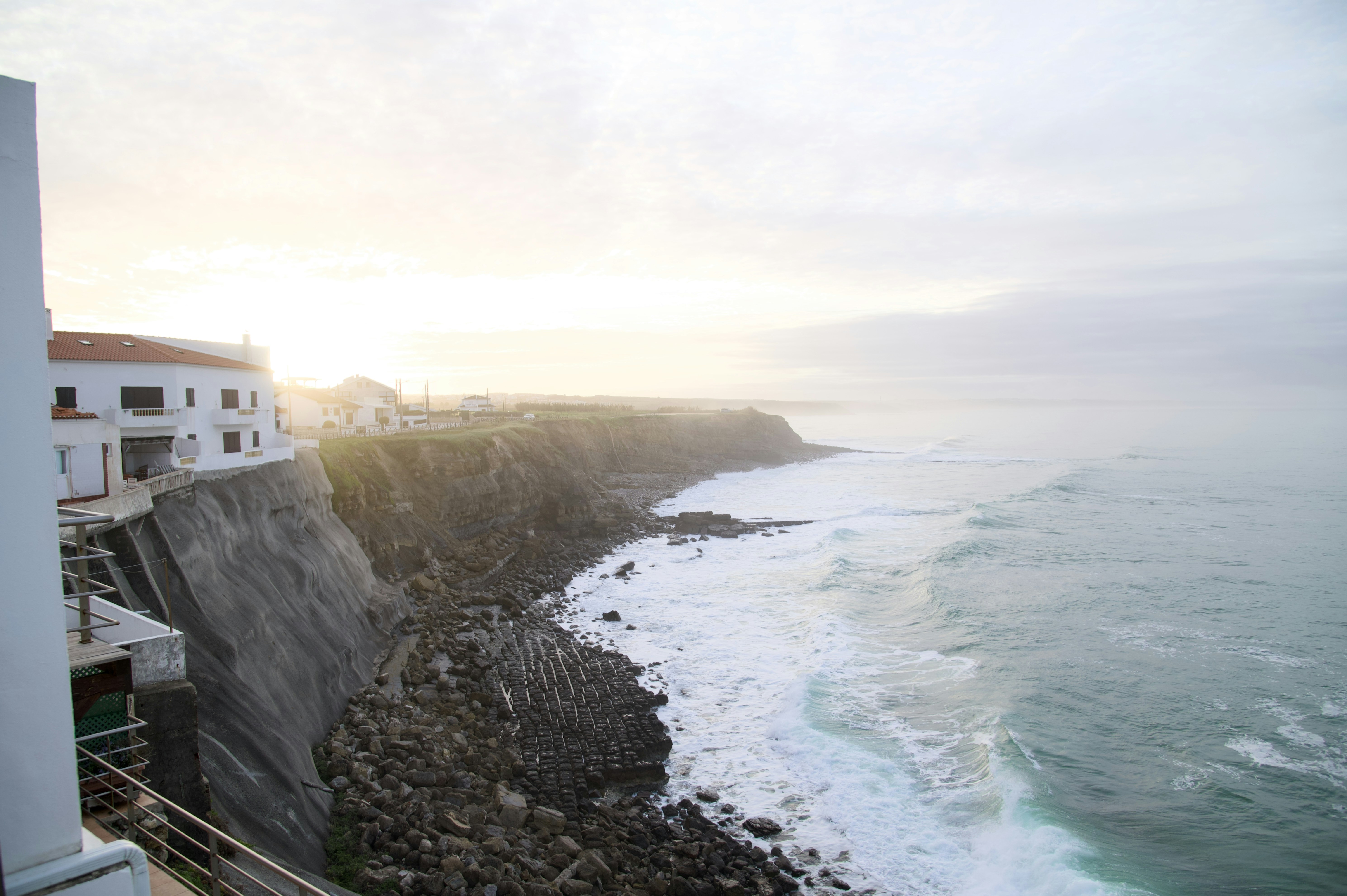 White building on a cliff overlooking the ocean waves