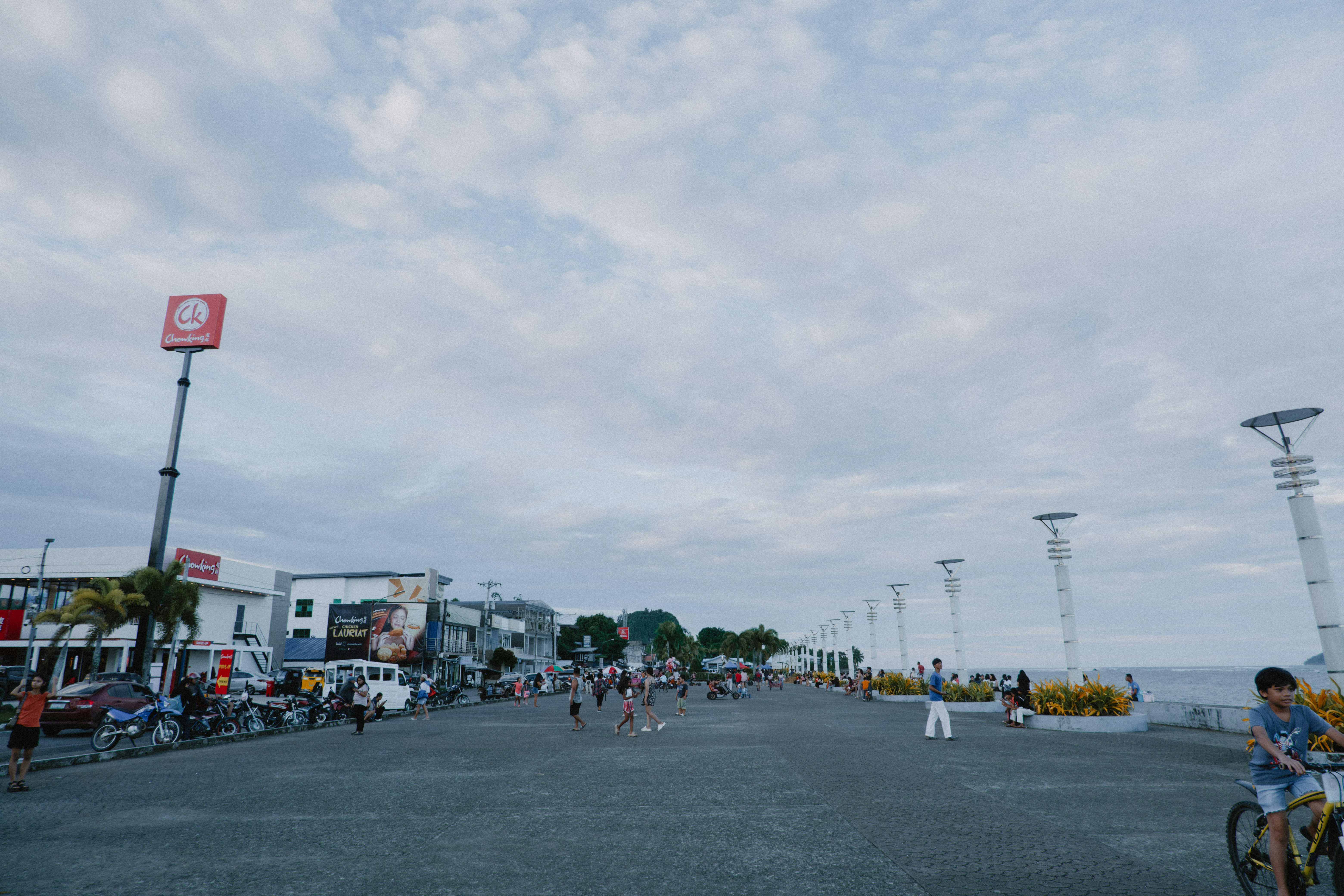La gente si raduna vicino alla costa sotto un cielo nuvoloso.