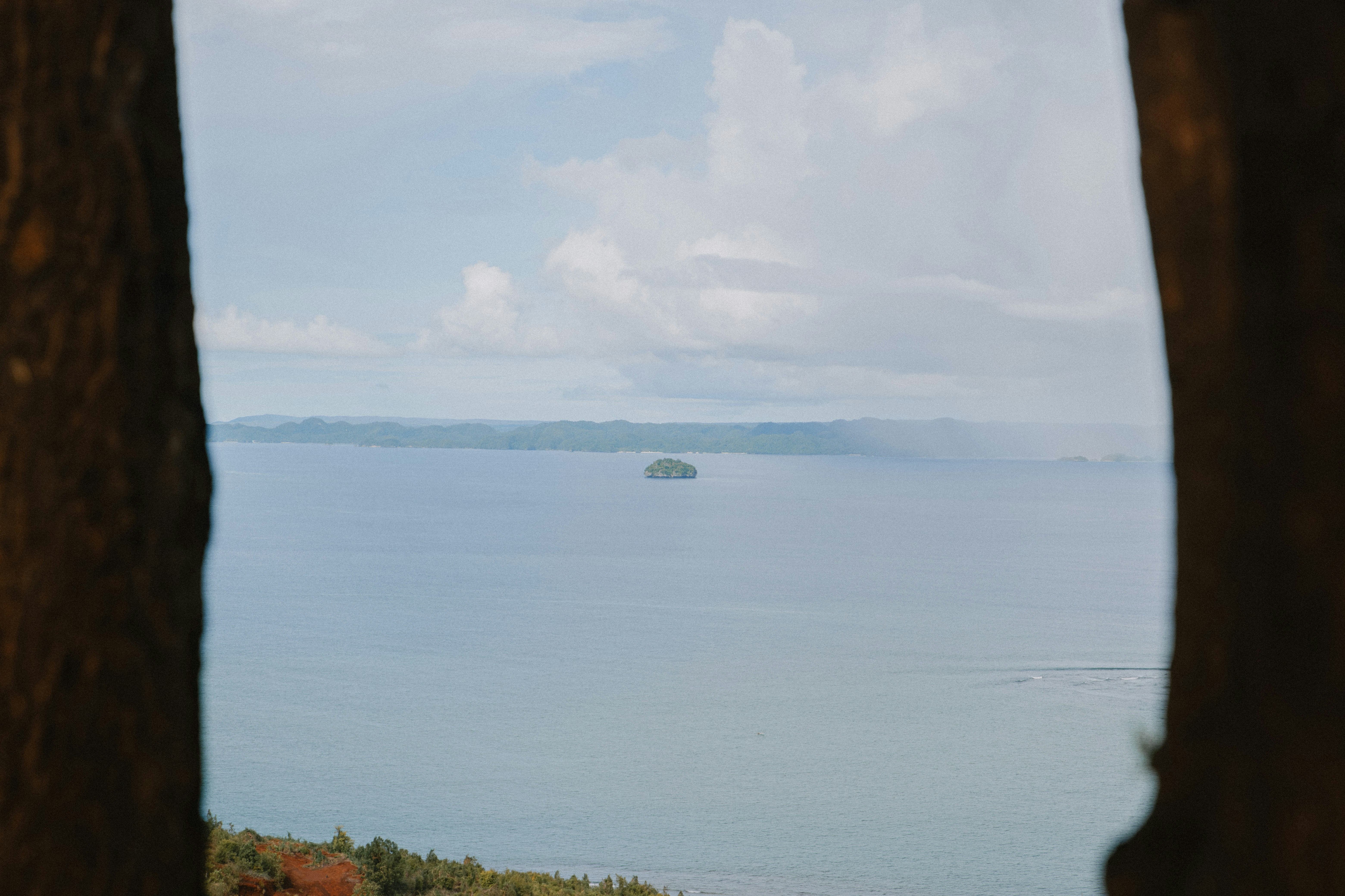 Mare calmo con un'isola lontana e cielo nuvoloso