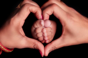 Parents hands form heart around baby's feet