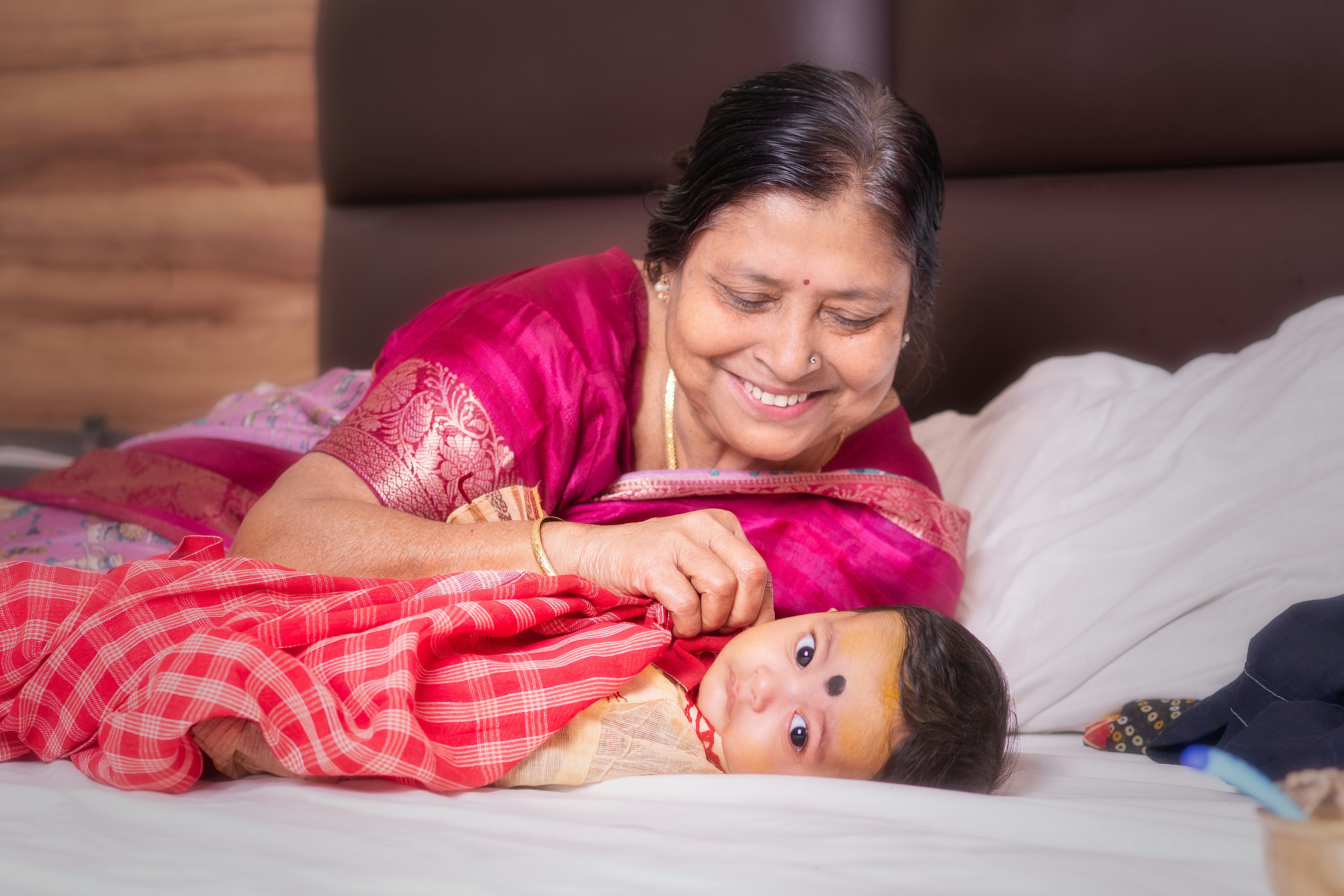 Grandmother smiling at a baby on a bed