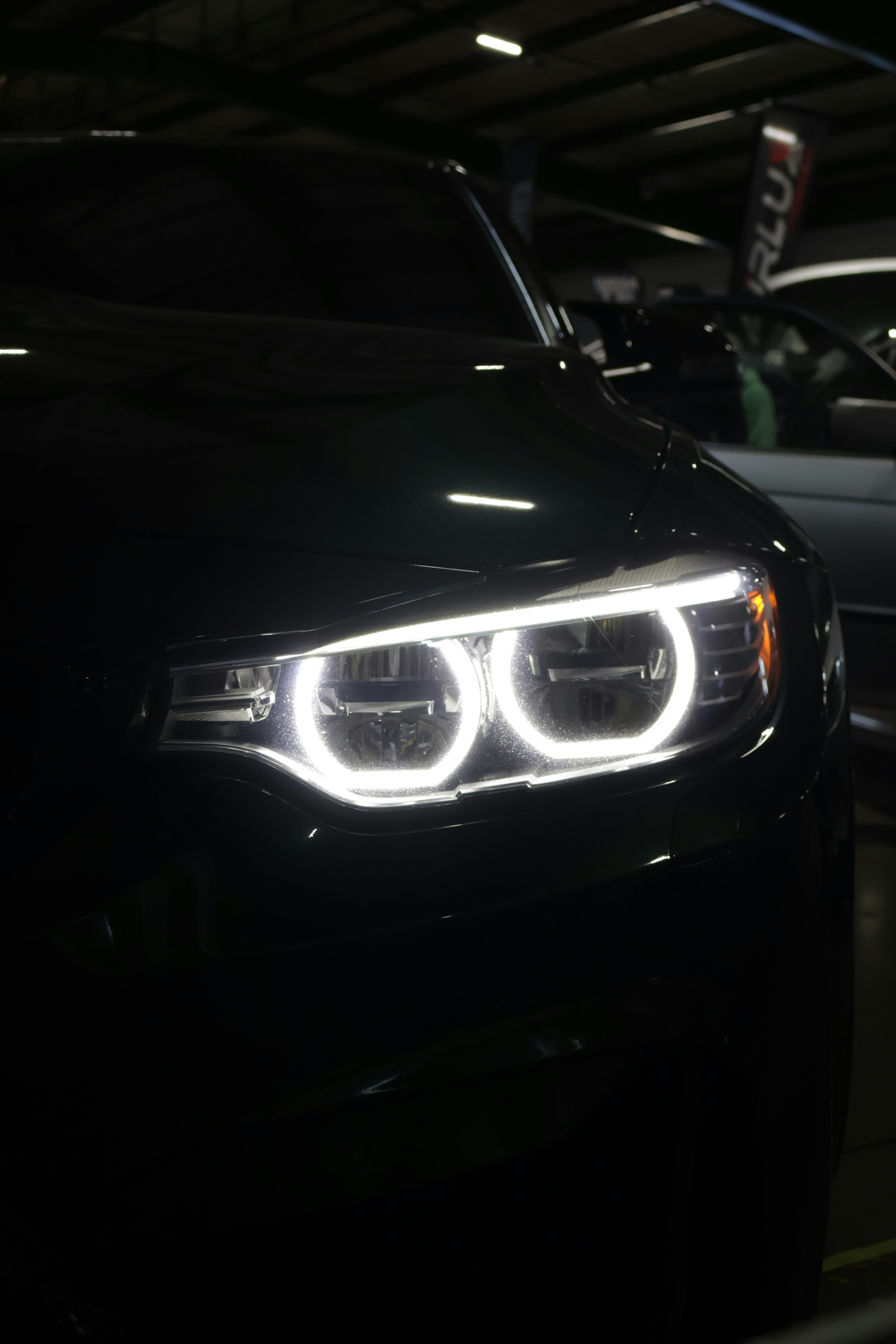 Close-up of a dark car's glowing headlights.